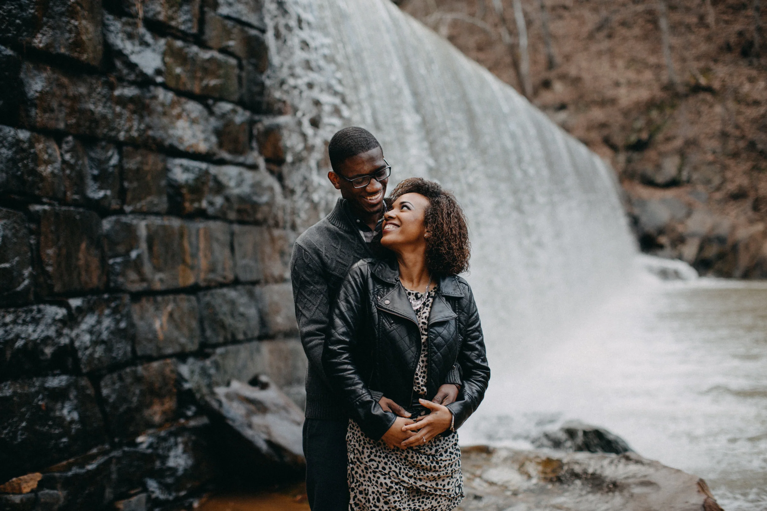 Couple embracing beside waterfall at Hollins Mill Park, in VA.