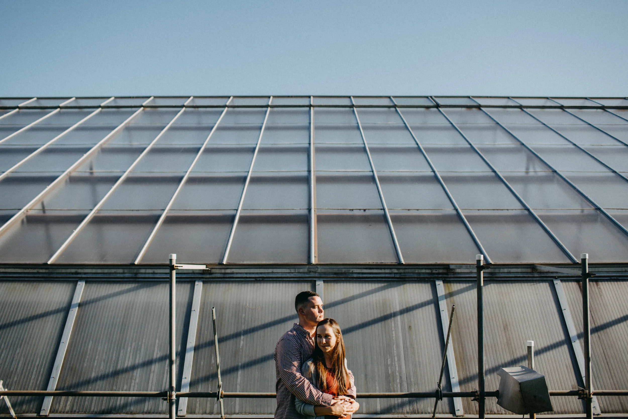 Couple embracing in front of greenhouse.