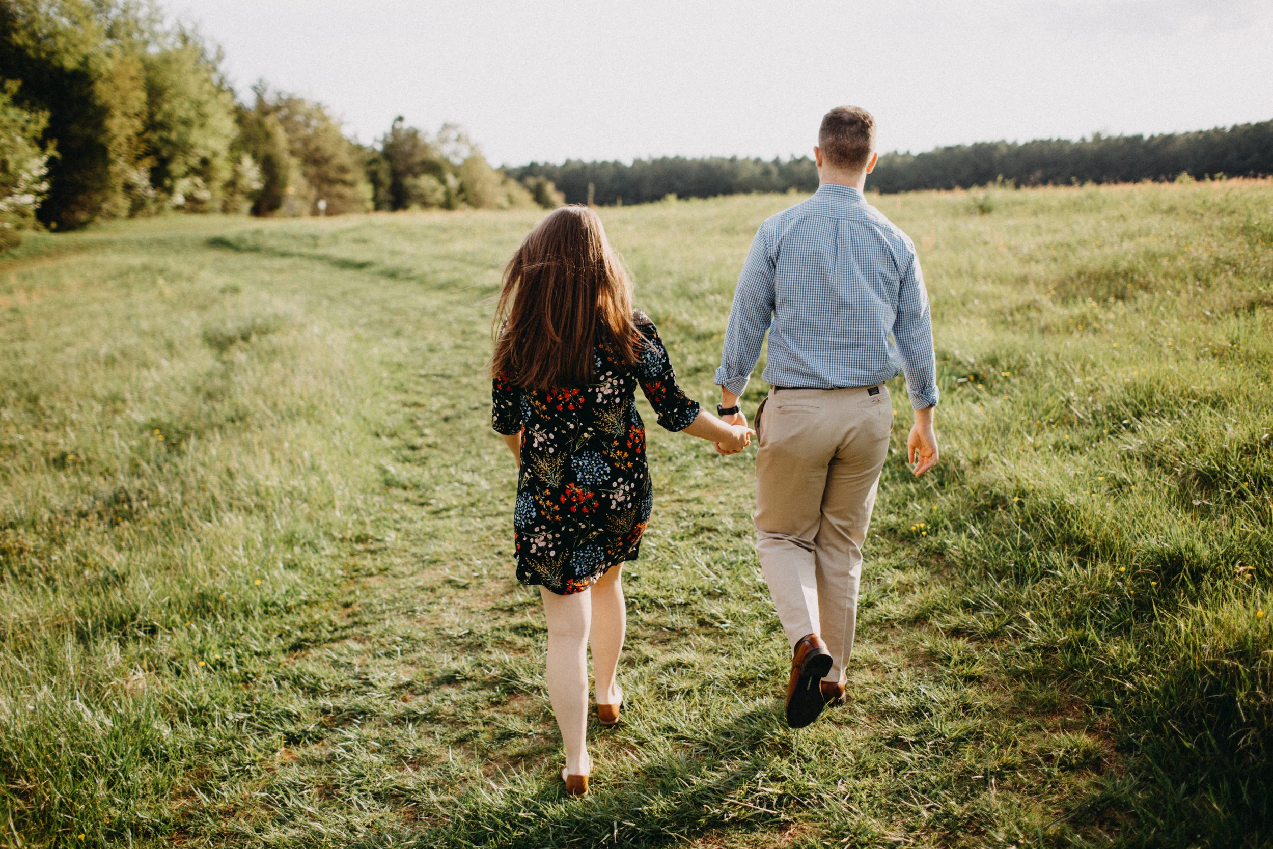 Couple walking together through field.