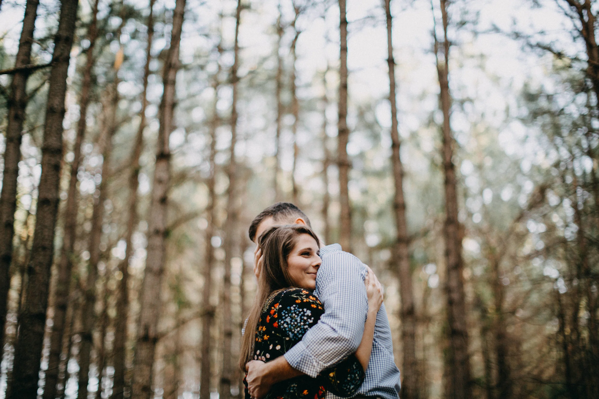 Couple embracing among trees.