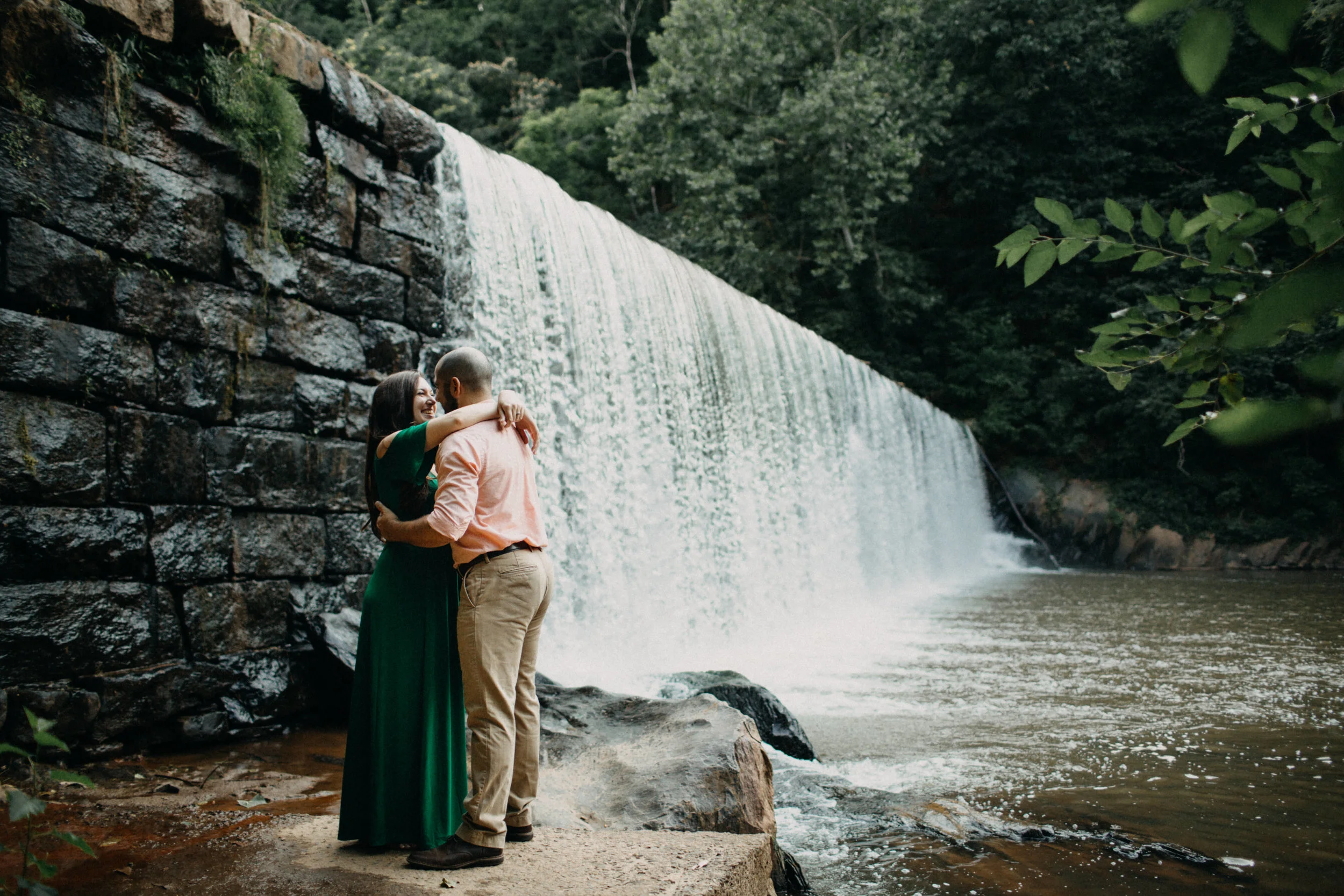 Couple embracing beside waterfall.