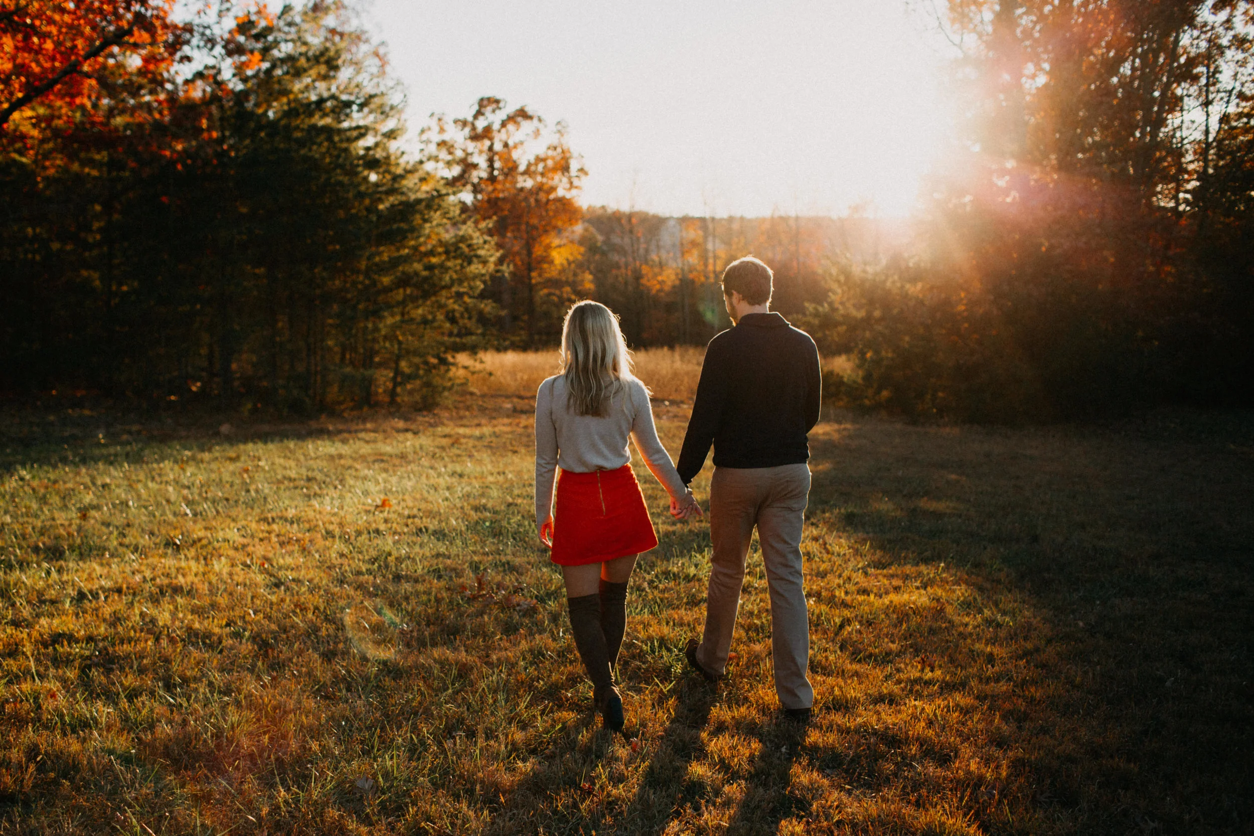 Couple walking through field at sunset.