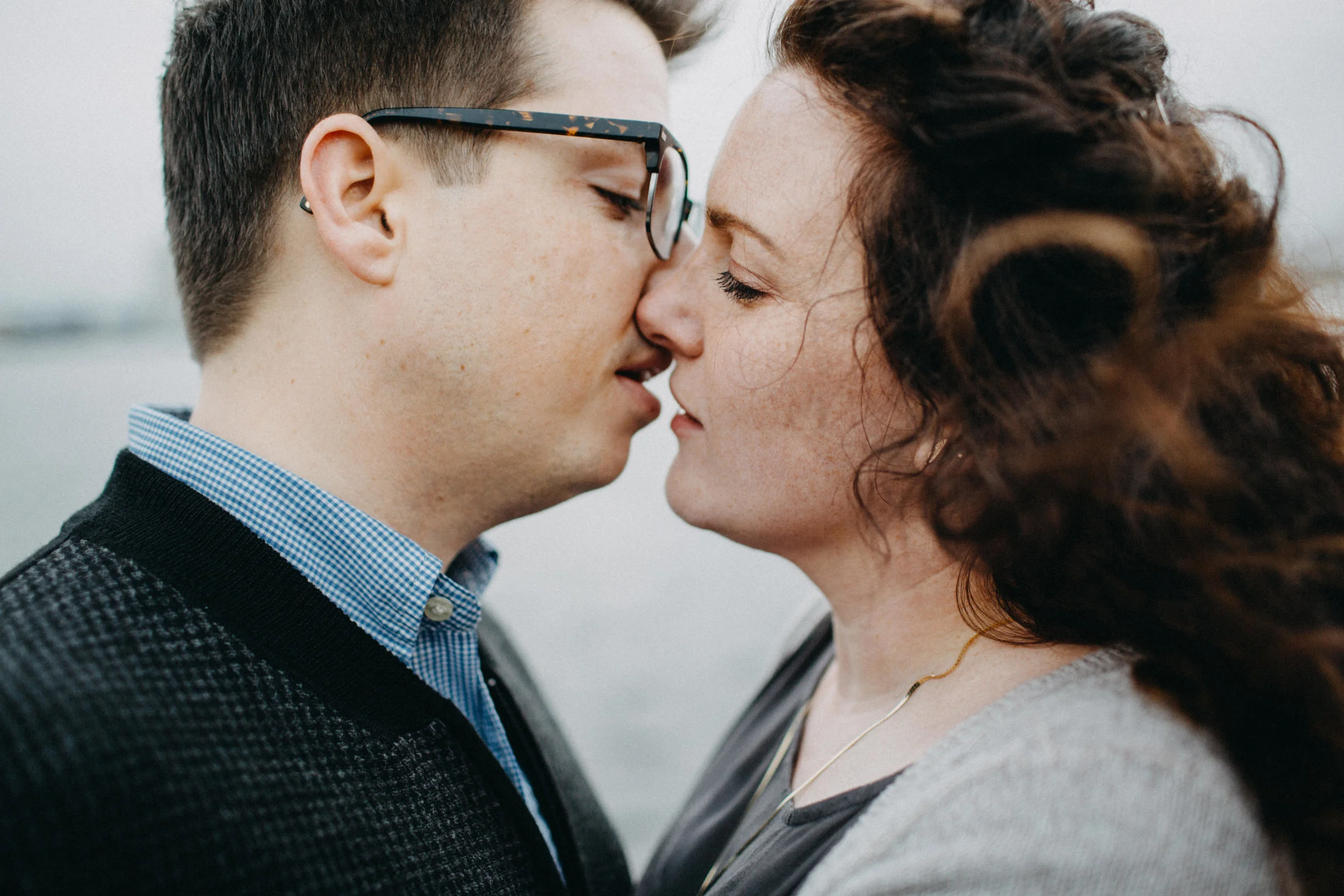 Couple leaning in for kiss, beside marina.