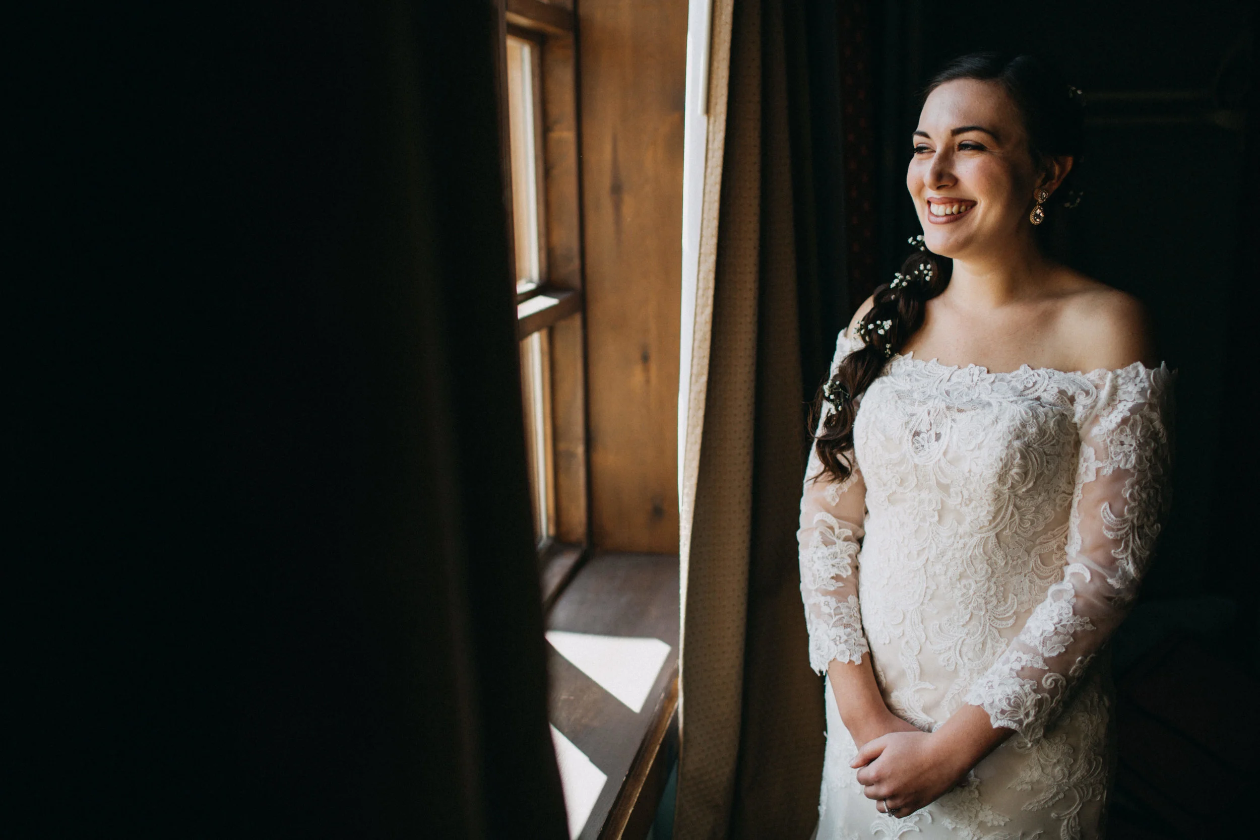 Portrait of bride standing beside window.