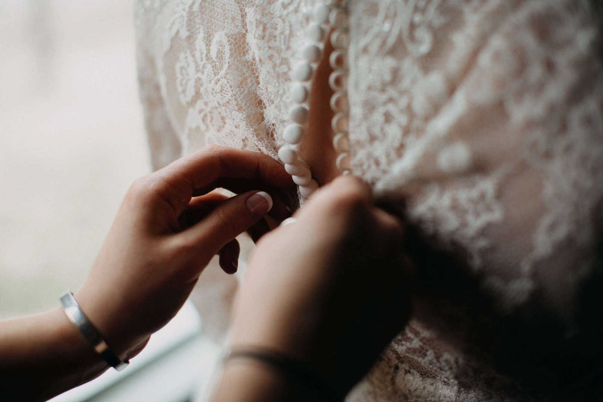 buttoning up bride's dress