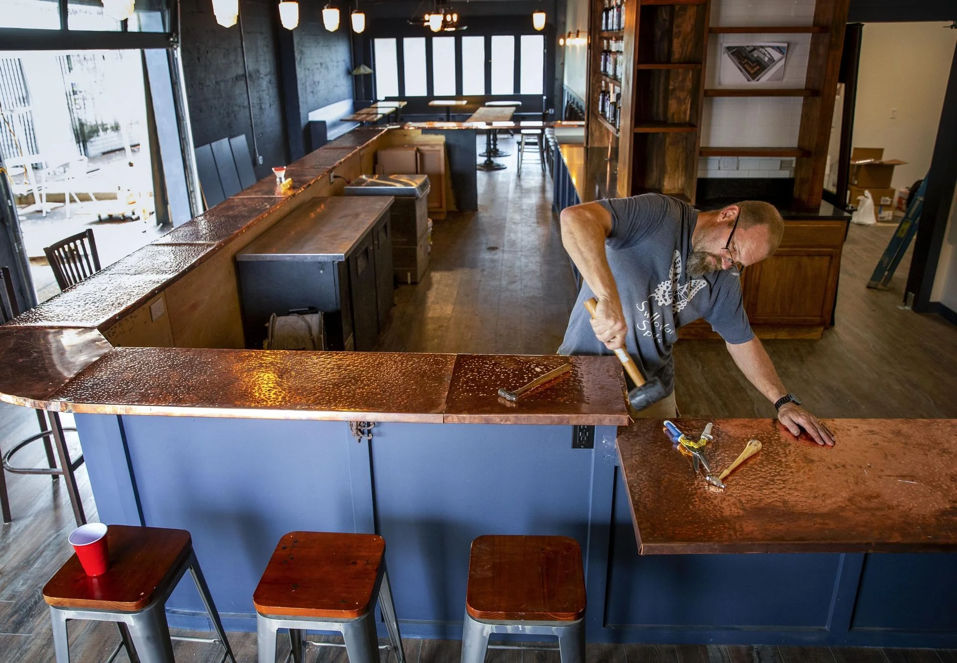 Swallowtail Spirits owner Kevin Barrett works on the bar top in his new retail space and cocktail lounge in Springfield where he will mix a variety of cocktails with his spirits. There is a full bar, outdoor patio and stage for music.