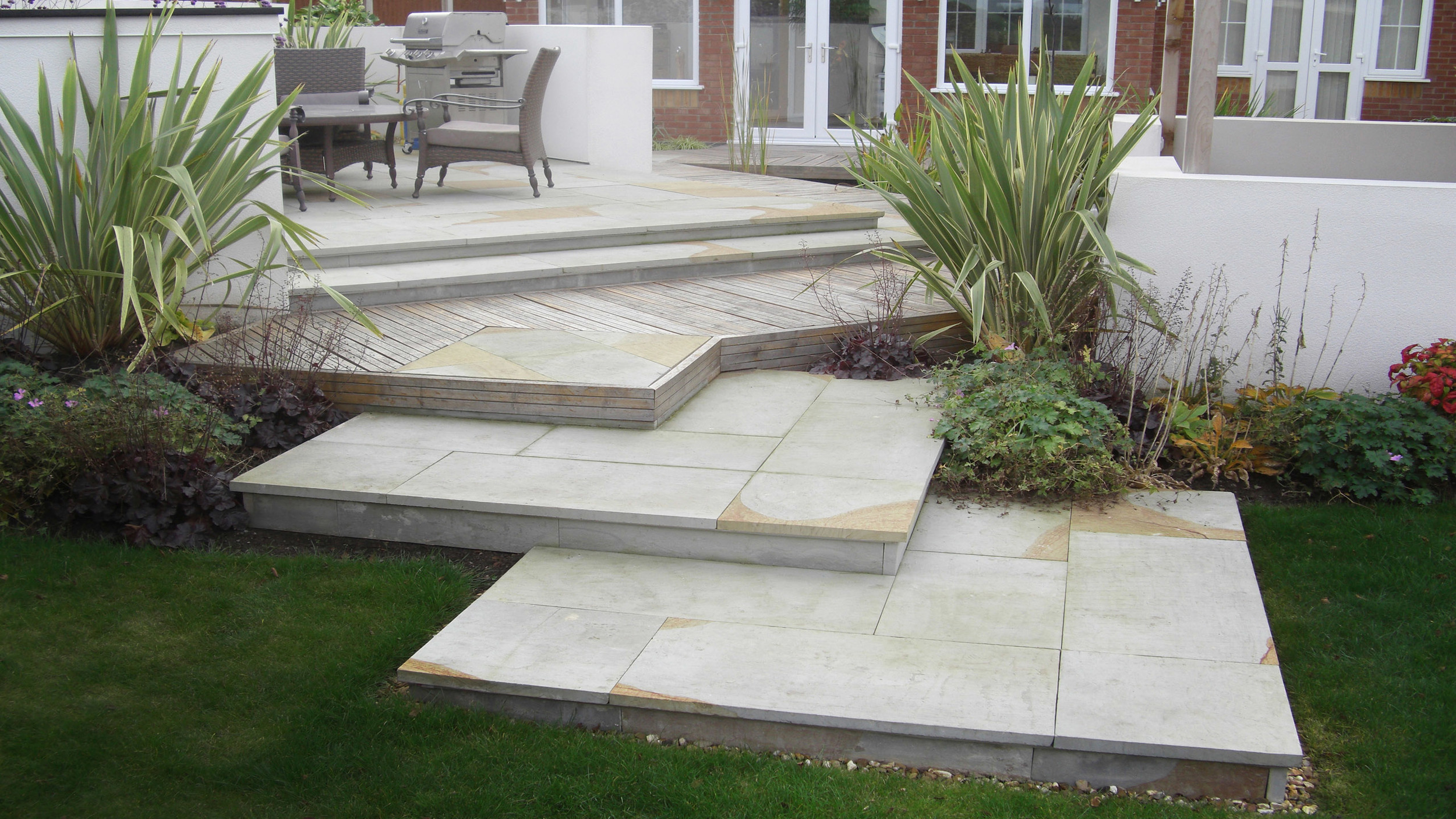 Contemporary garden steps with dining area and lawn.