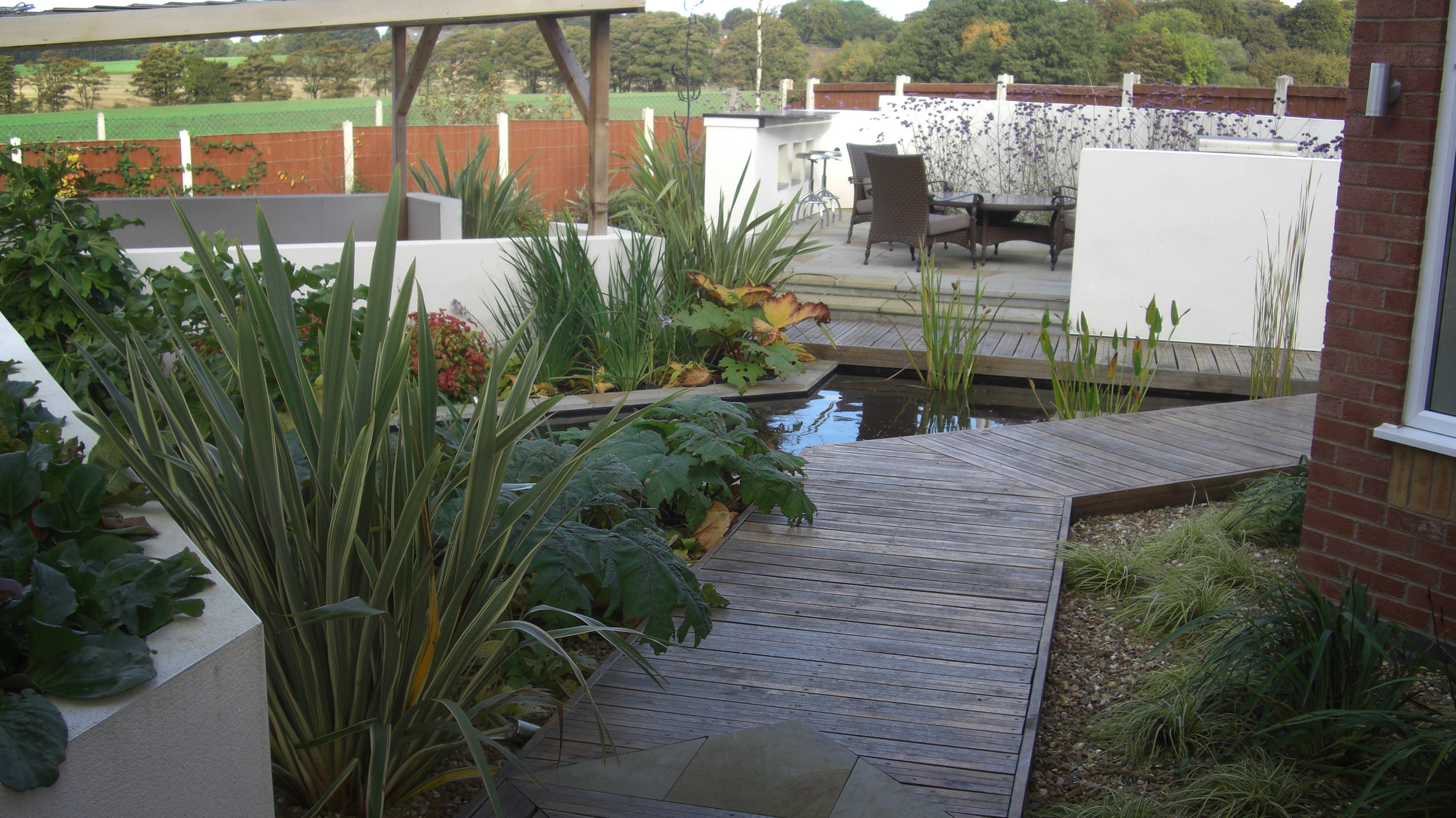 Contemporary garden designed with a water rill, dining area and a cedar shelter