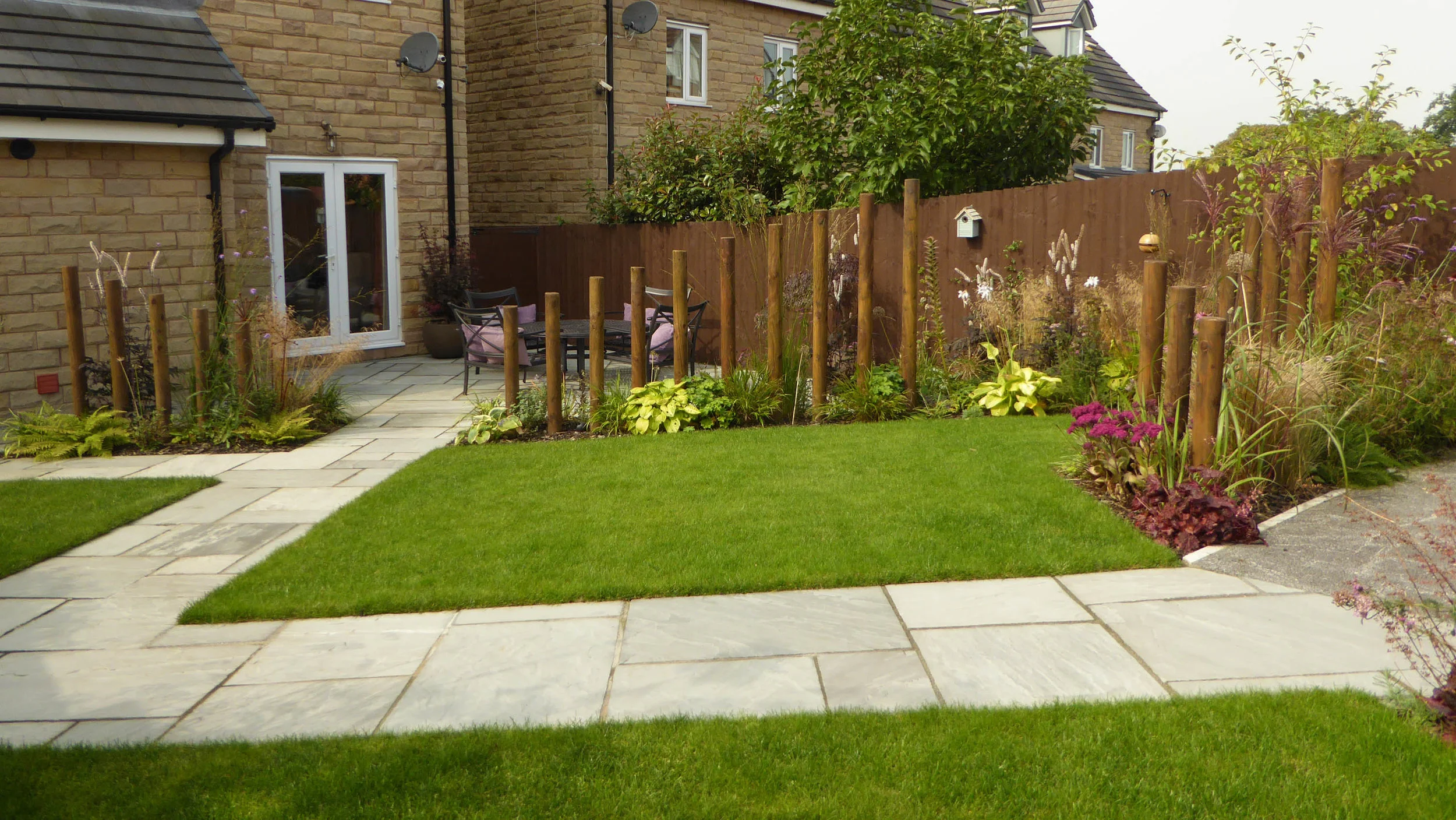 AFTER - New lawn with drainage and planting beds broken by pathway to and from car port.