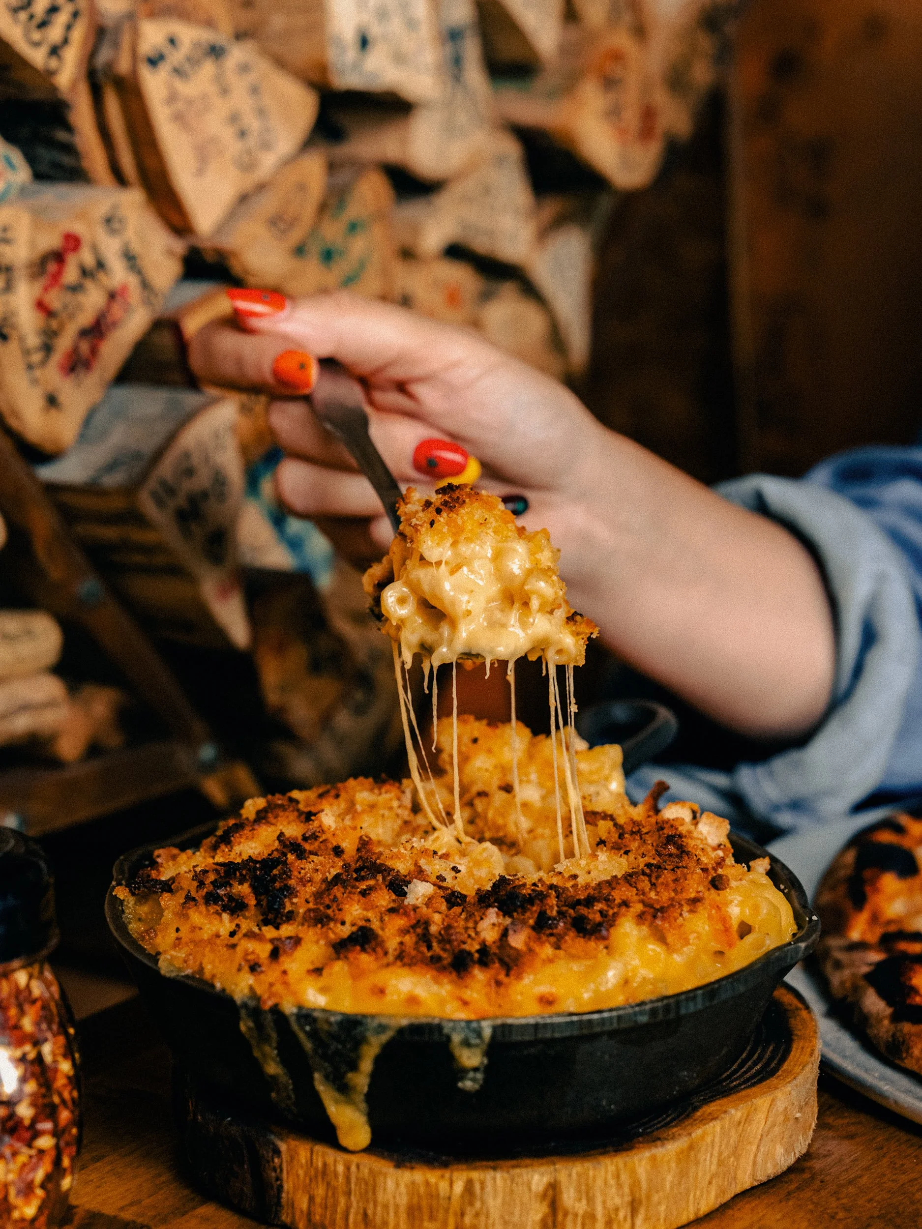 Cheese pull from a cast iron skillet of Angel's mac & cheese at One6Three pizza shop