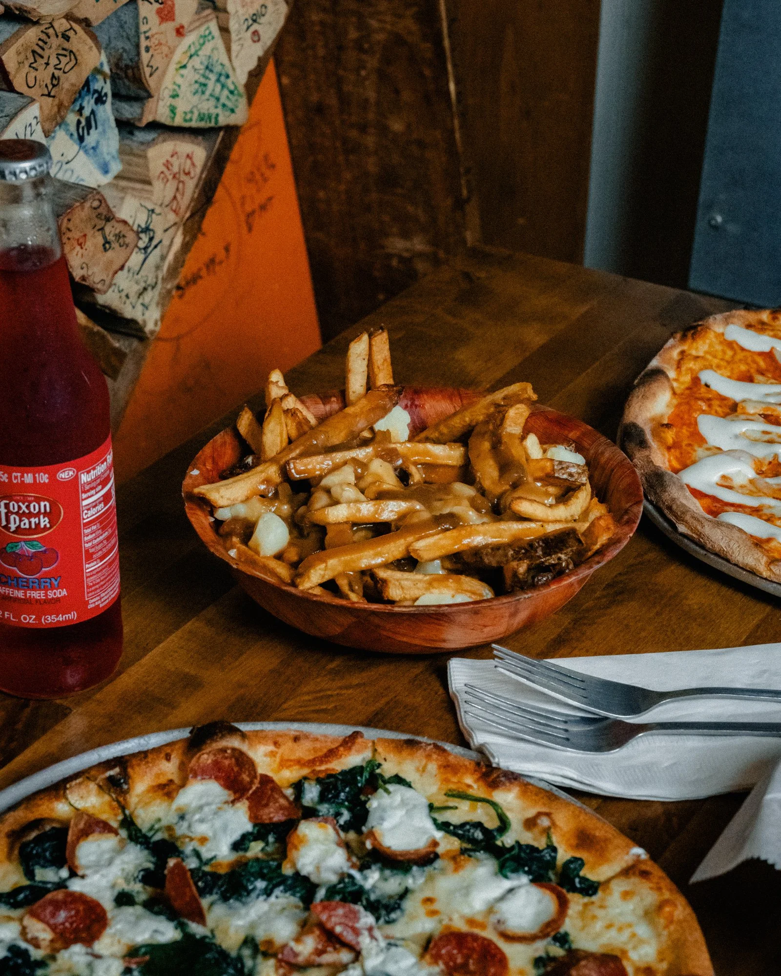 Poutine, wood-fired pizzas & a Foxon Park soda on a wooden table at One6Three in New Haven