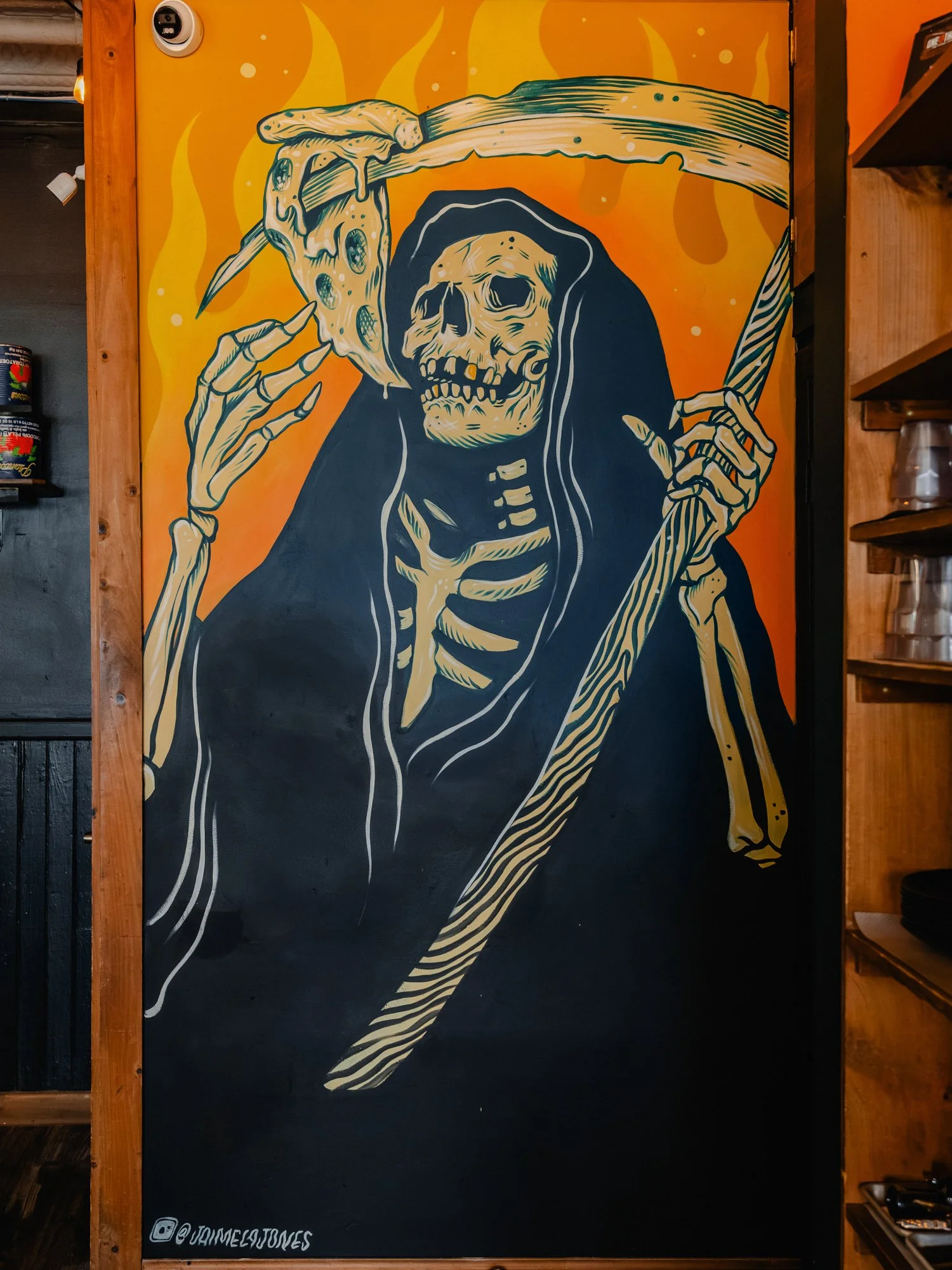 Reaper eating a slice of pizza, mural by Jaime La Jones inside One6Three pizza shop