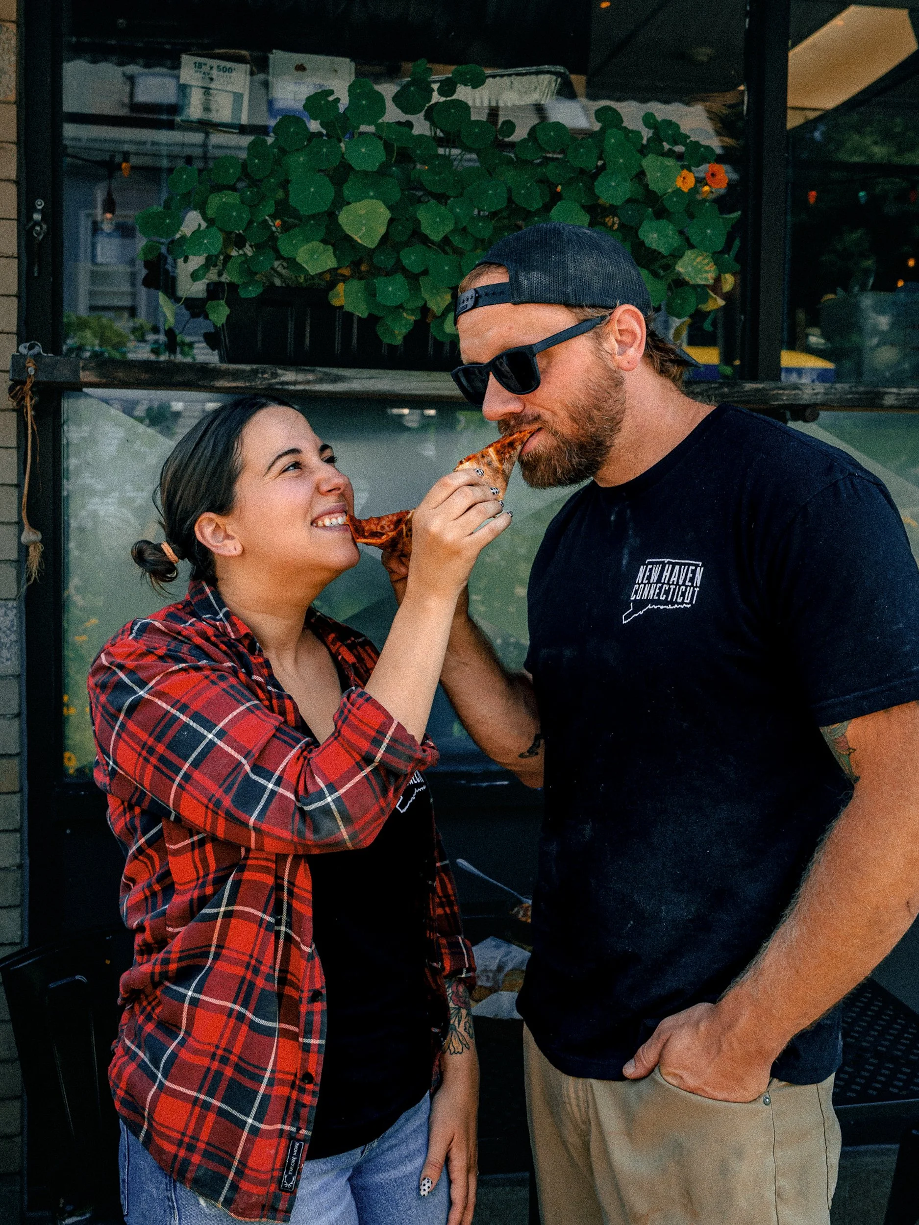 Owners Alexa & Andrew sharing a slice of pizza outside One6Three in East Rock, New Haven