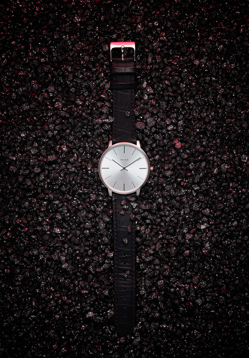  Pilgrim watch slightly buried in small volcanic rocks glowing with heat. Still Life Photograph by London Based Still Life Photographer Andy Carson 