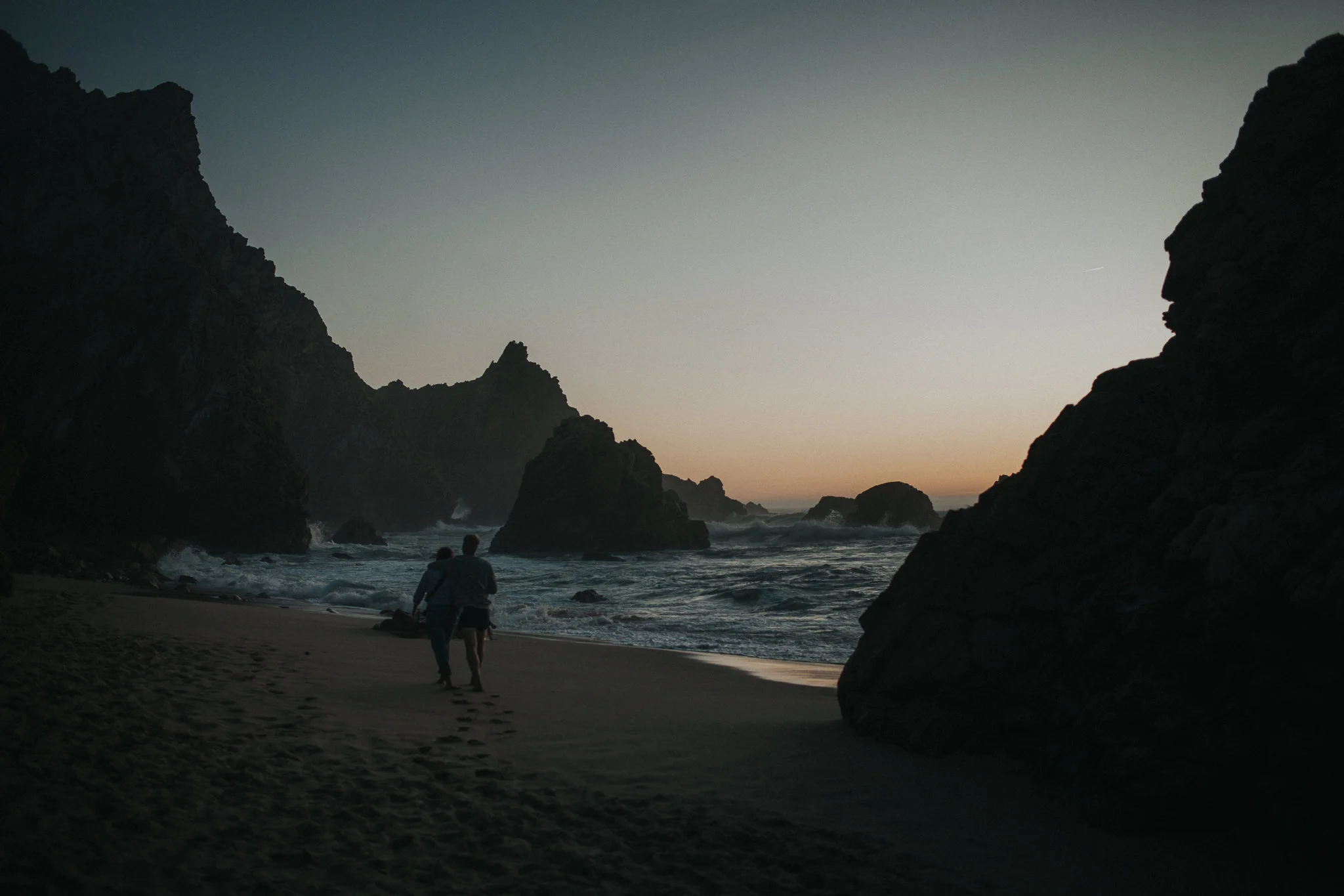 Couple walking at Praia da Ursa during sunset