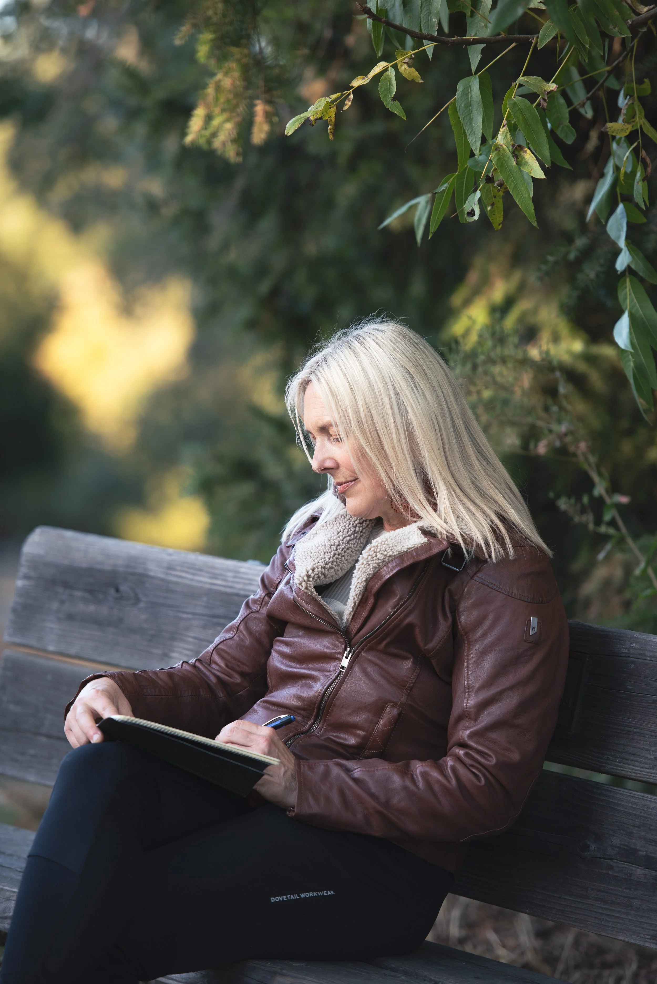 woman writing in journal on a park bench 