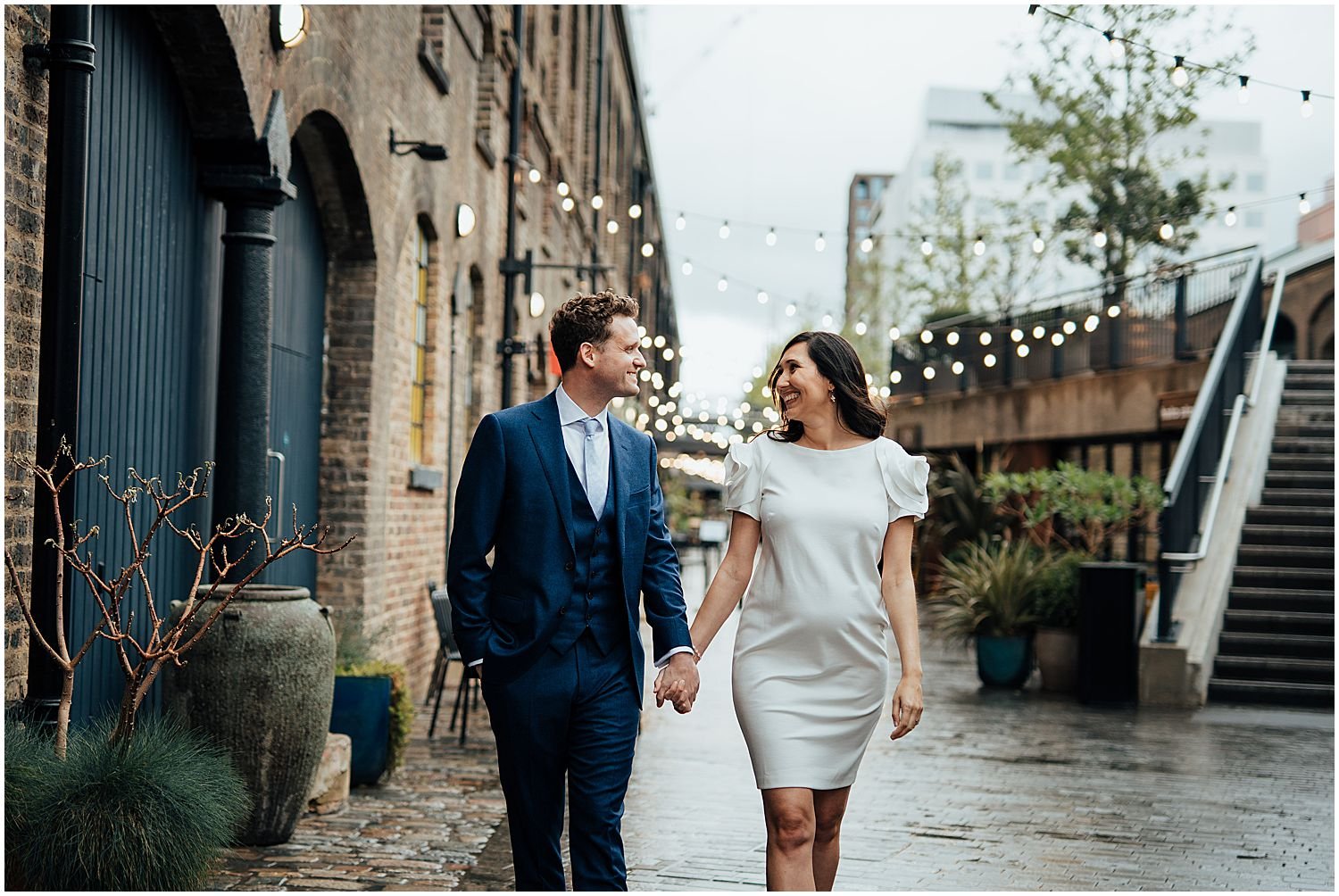 London elopement photos - bride and groom walking under fairy lights in Kings Cross