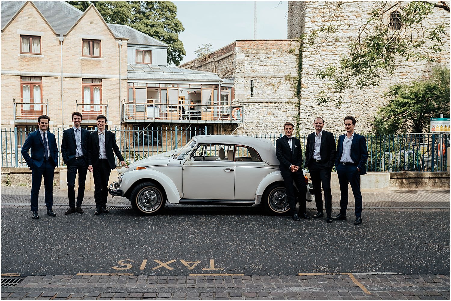 Groomsmen in Oxford with white wedding car