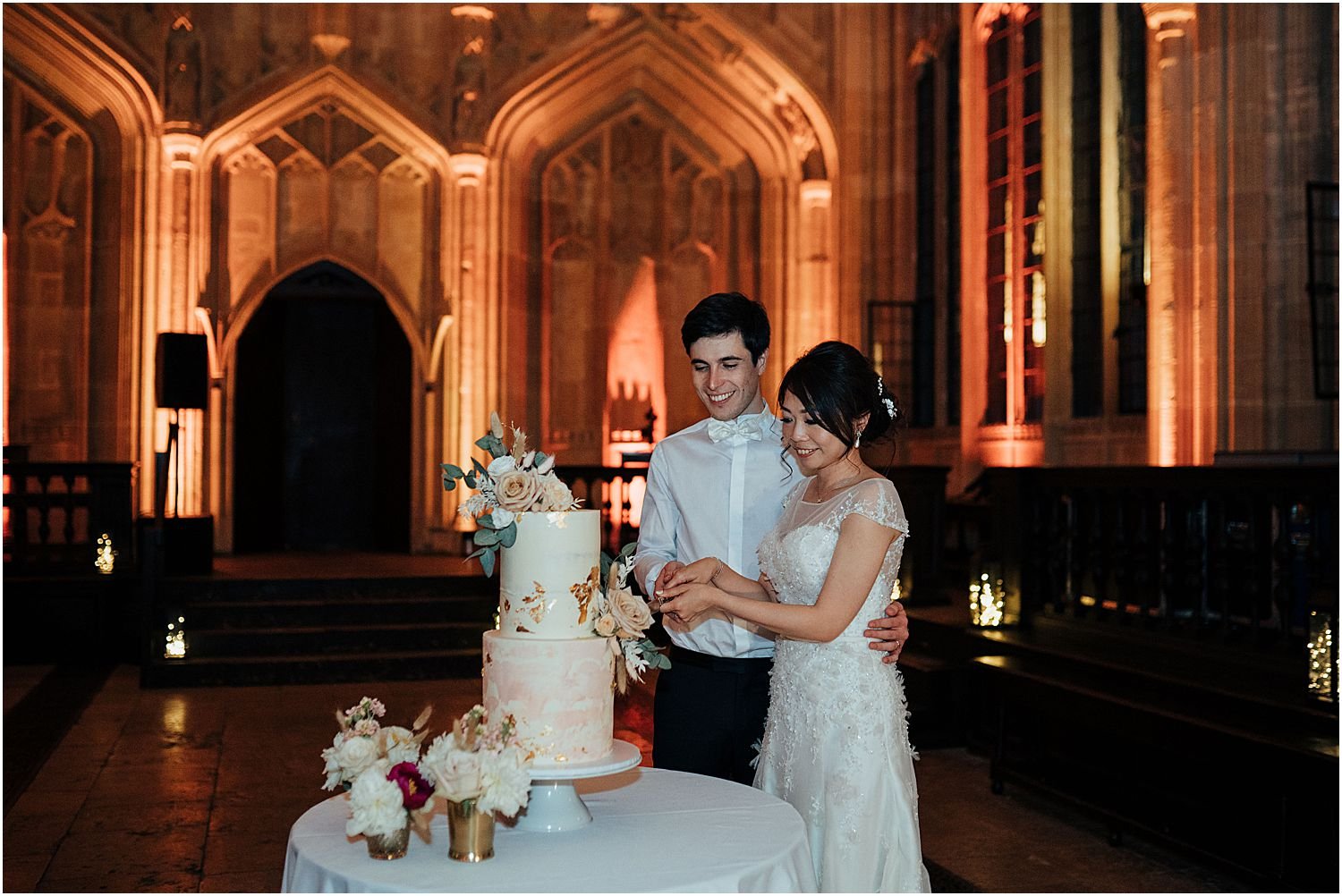 Bride and groom cutting cake in Divinity School Oxford