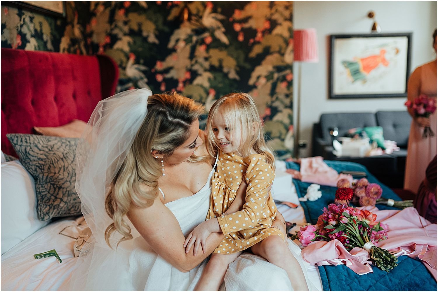 Bride and flower girl sitting on bed