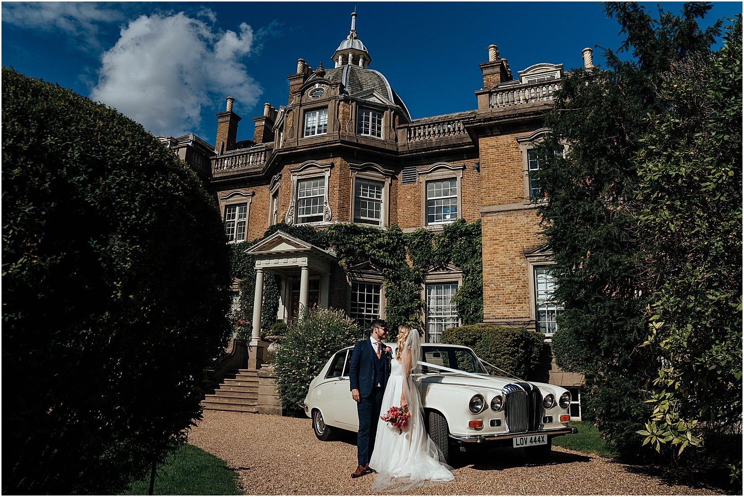 Bride and groom with wedding car outside Hampton Court House