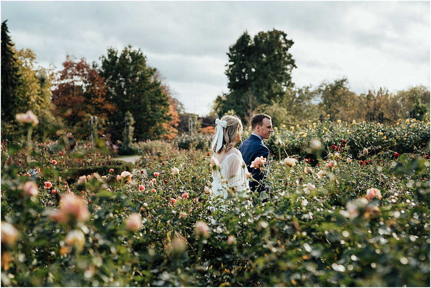Bride and groom walking rose gardens