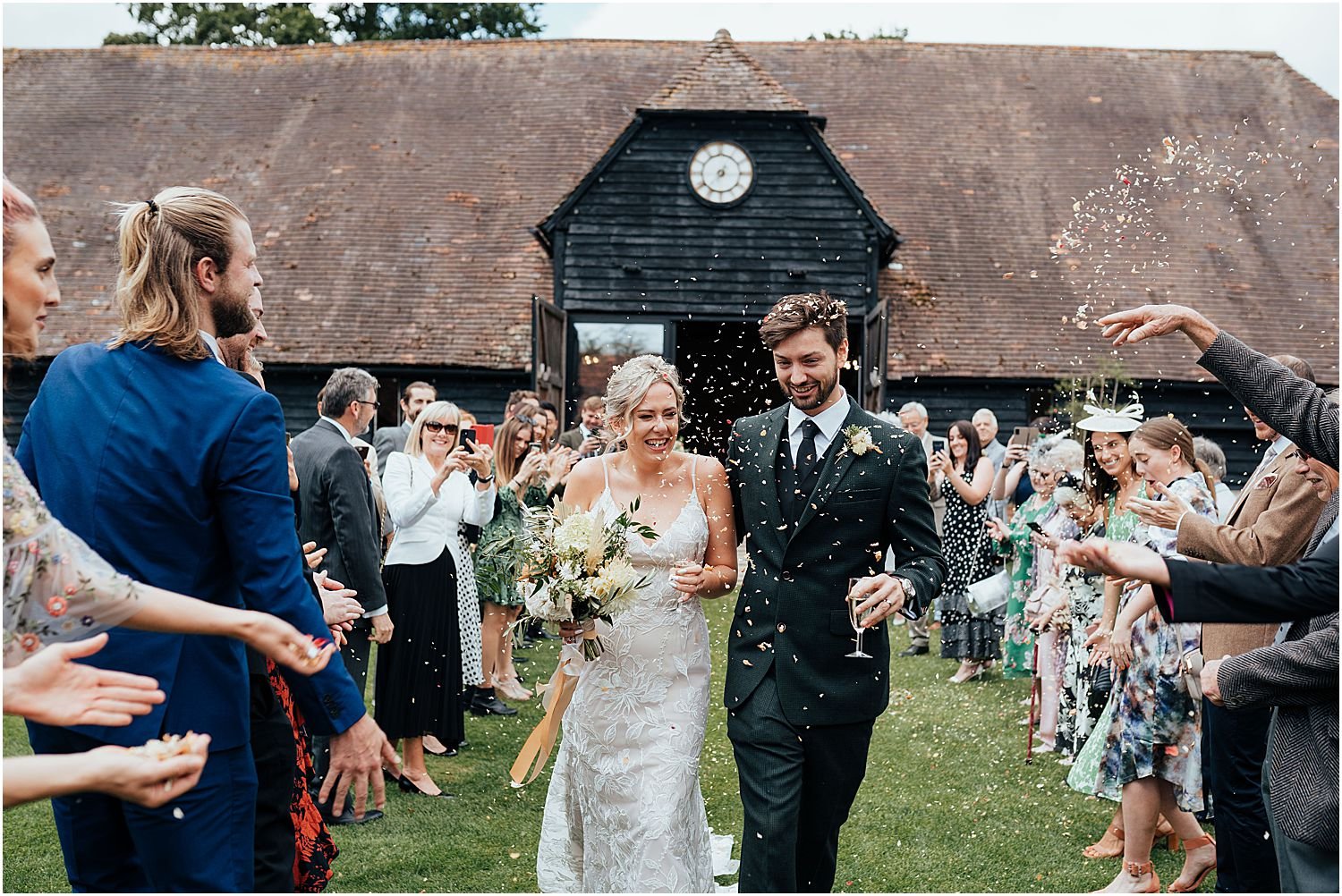 Guests throwing confetti at couple outside barn