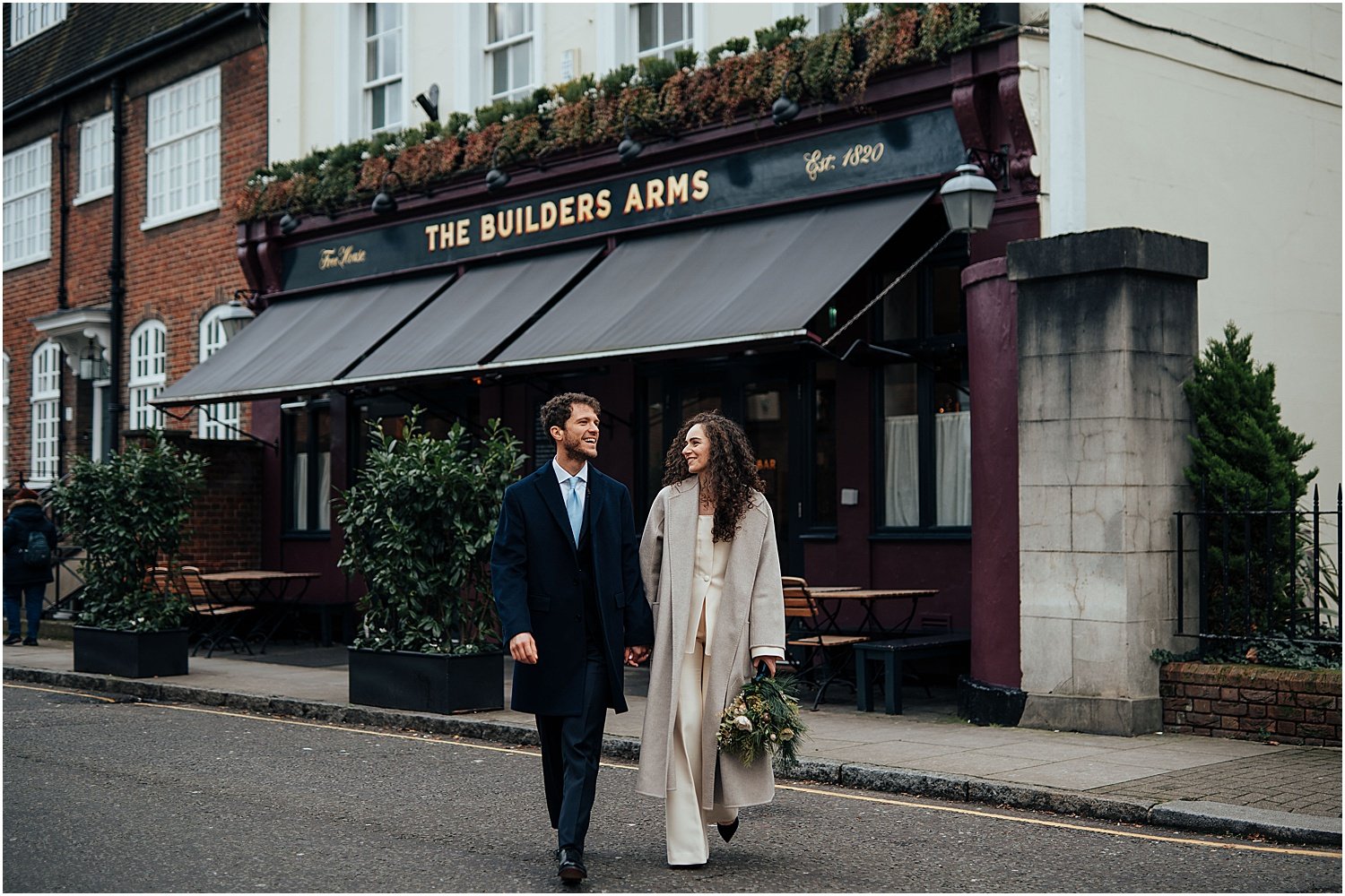 Bride and groom walking in front of pub