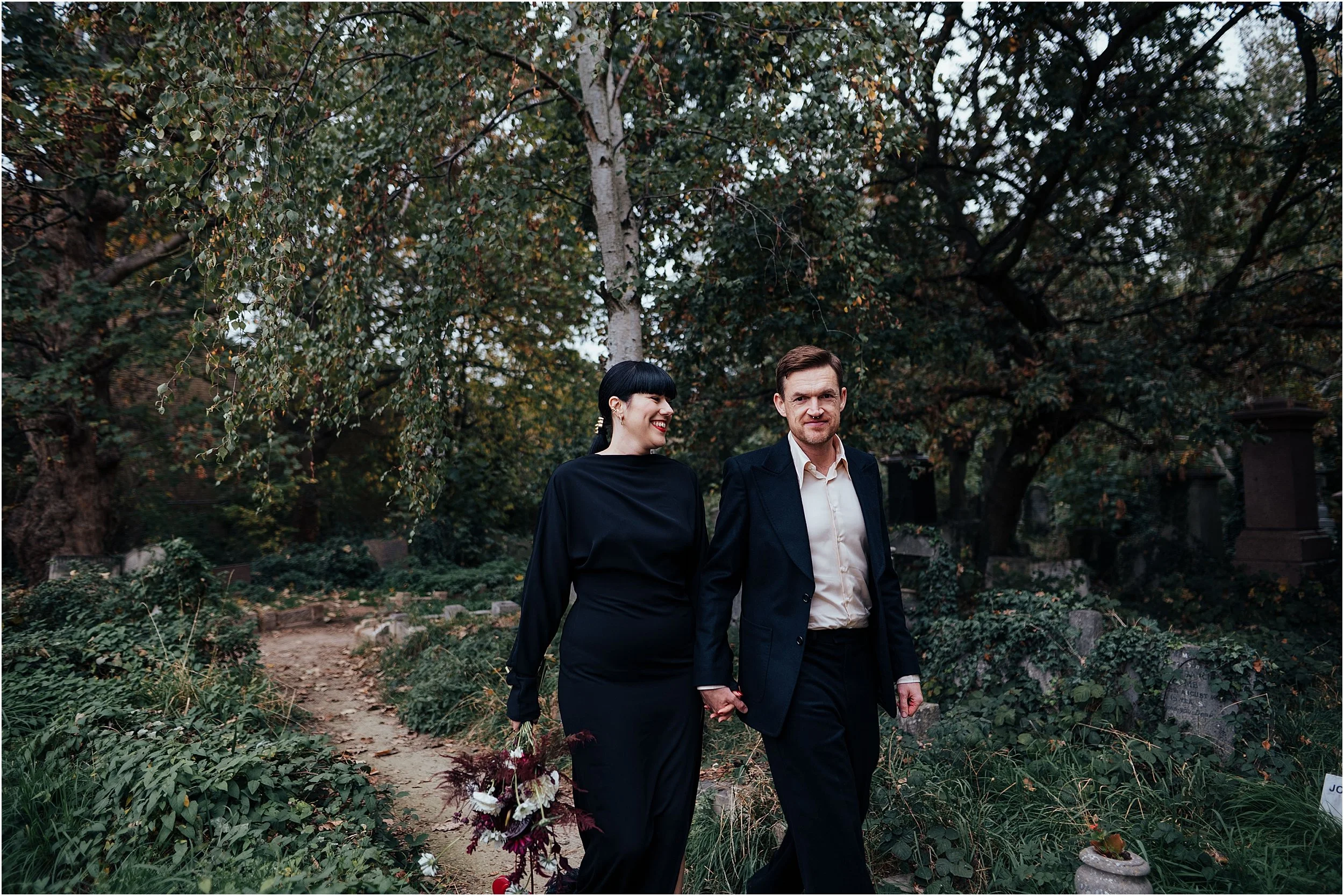 Bride and groom walking among cemetery in Abney Park