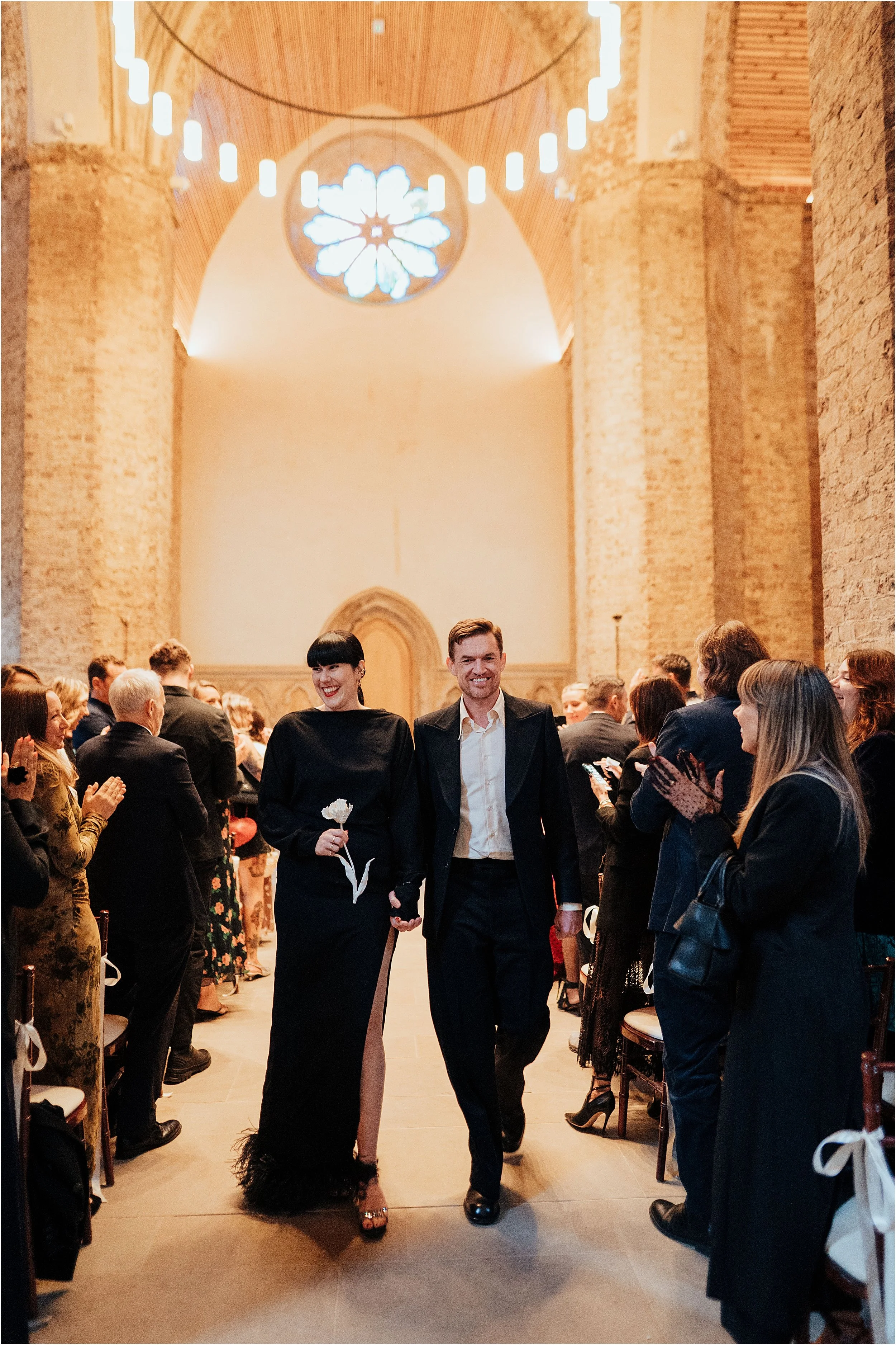 Newlyweds leaving chapel with guests applauding