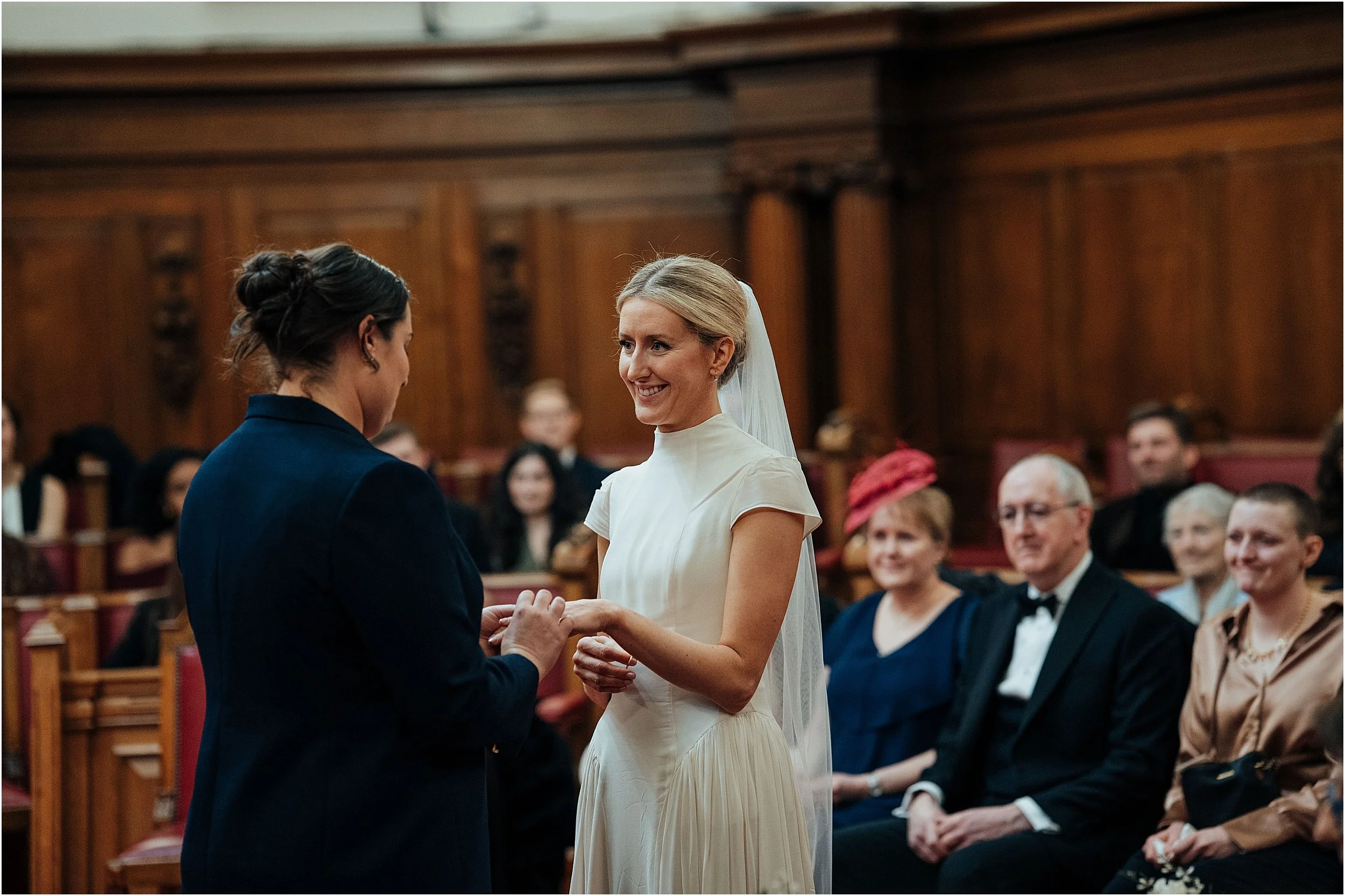 Lesbian couple exchanging wedding vows in council chamber 