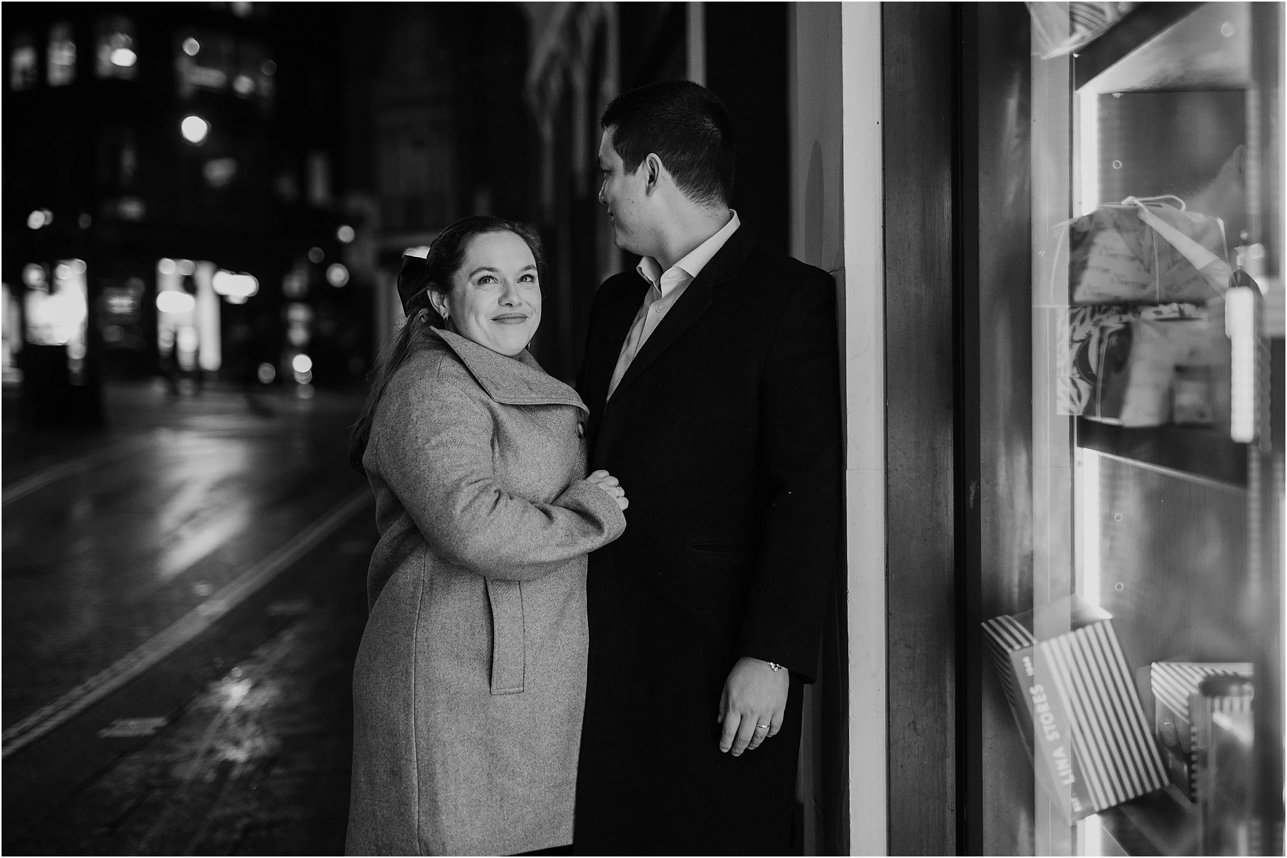 Newlywed couple sheltering from rain outside London shop on their winter wedding day