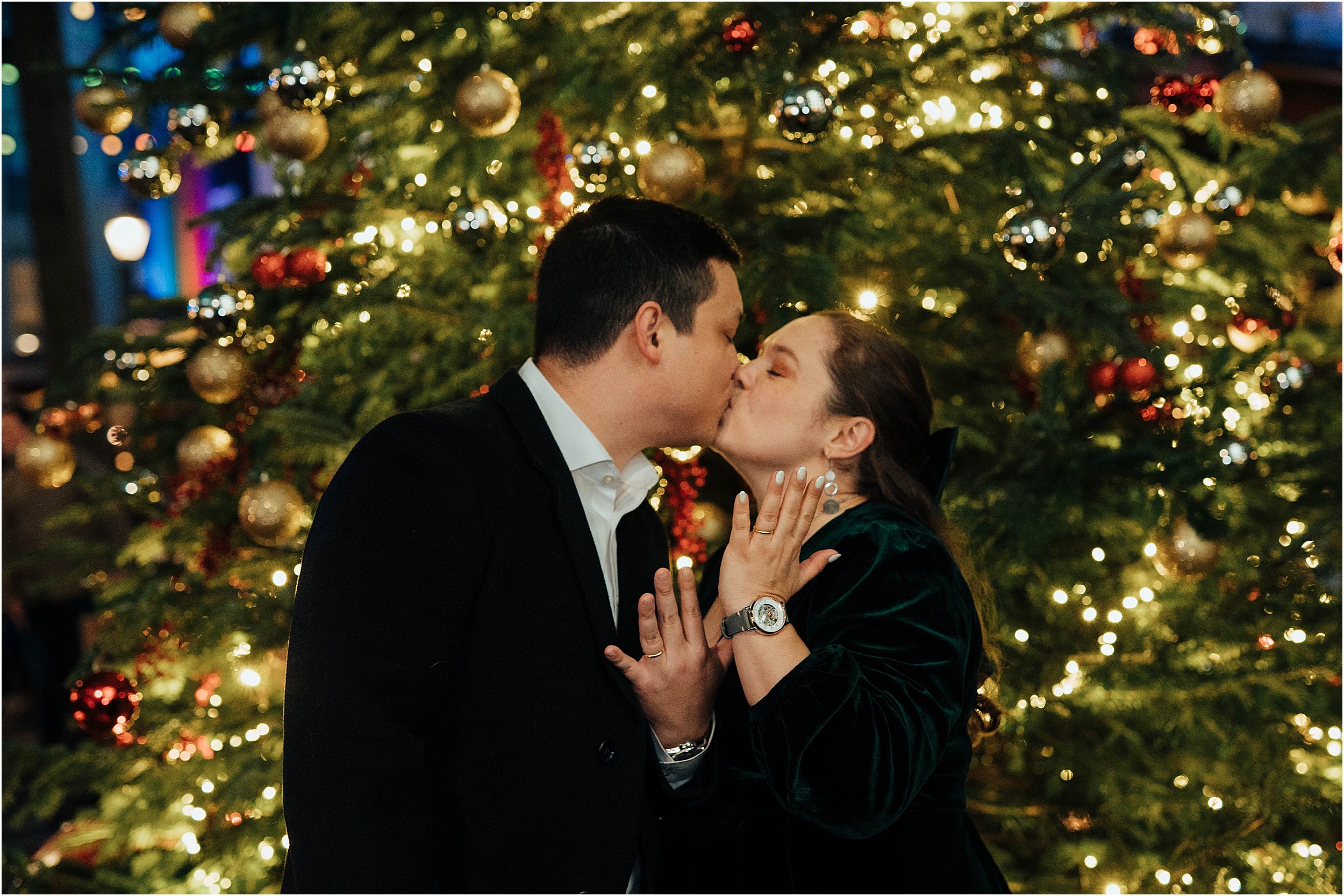 Bride and groom showing their wedding rings in front of Christmas tree
