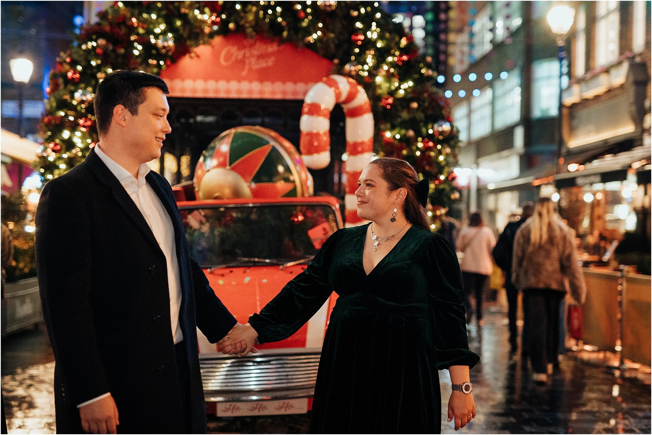 Newlyweds standing in front of colour food stall at Christmas market in London