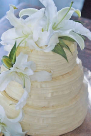 Almond Cake, Vanilla Custard Filling, Honey Buttercream Frost Casually Ruffled Cake with formal white lilies strikes a rustic and elegant balance.