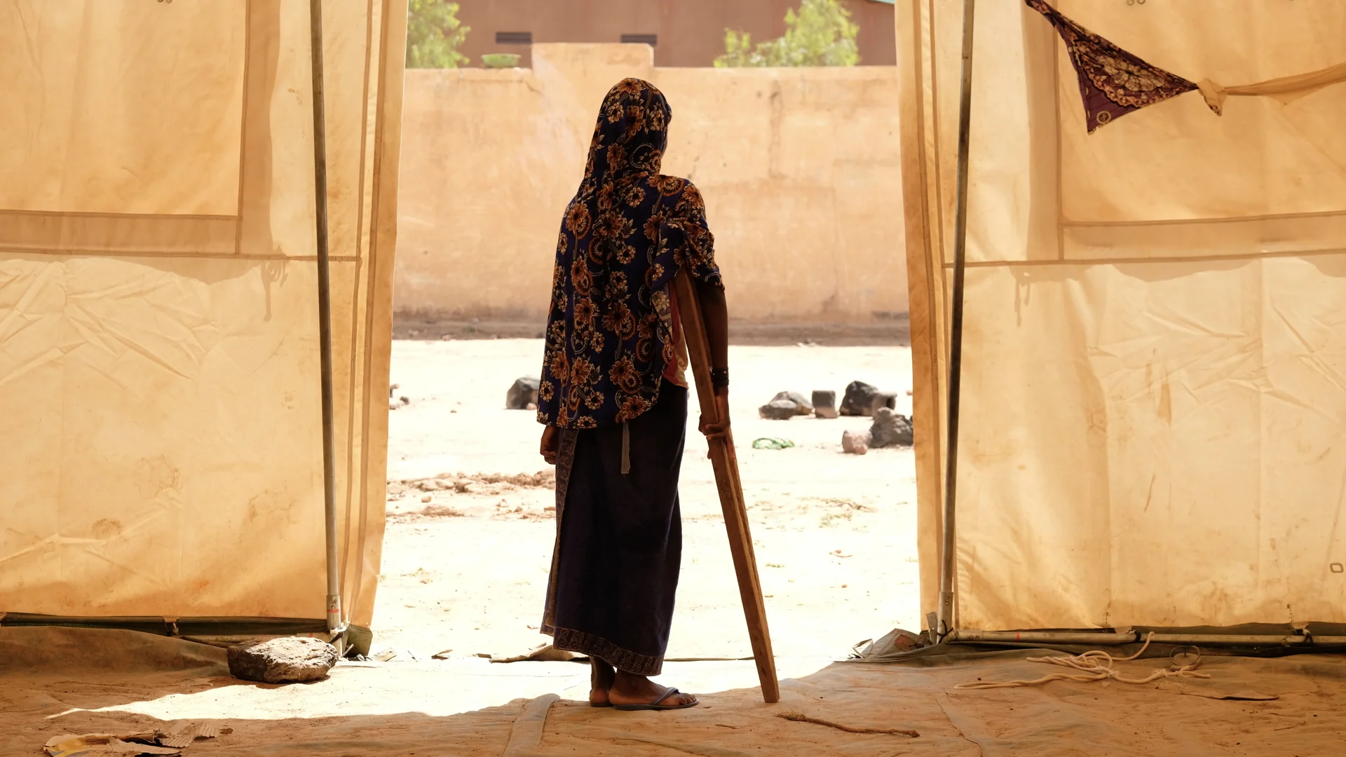 Awa stands outside the door of the tent of a temporary school in a camp outside of Mopti. Her mother was killed in an attack on her village and she was shot in the leg. She’s recovering in the safety of the camp but says she’s still in pain and stru…