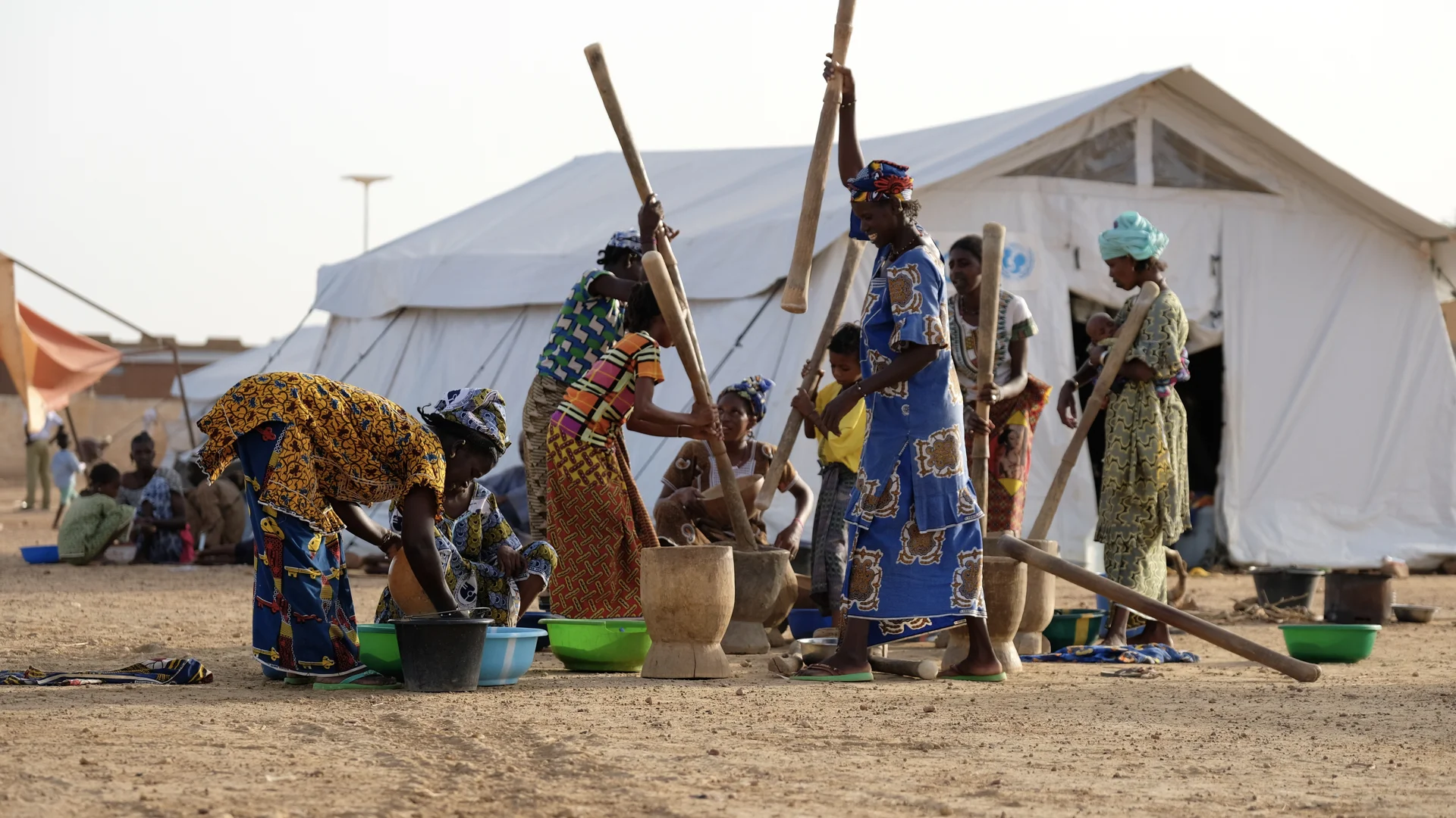 Women who have been displaced from their homes after violent attacks try to get back to normal life at the camp where they’ve found shelter outside of Mopti. Traditional techniques of pounding the grains continue, even in the challenging conditions.…
