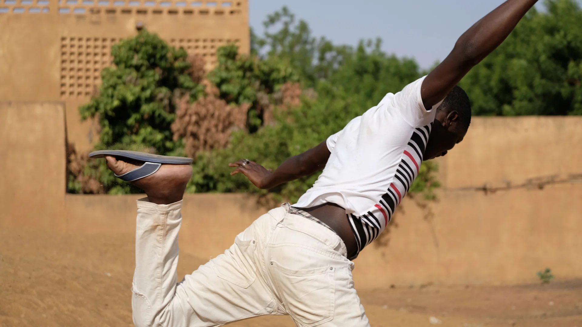 Mamadou, age 15, was associated with an armed group for self-defense in the Mopti region of Mali. He jumps into the air outside the center where he’s found shelter while waiting to go home to his family. He’s excited to get some skills training so h…