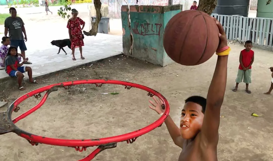 A boy goes in for a slam dunk on an improvised basketball court under a tree outside his home in Majuro. Basketball is popular as a result of American influence, but the more corrosive influence of the American diet of imported foods has taken a tol…