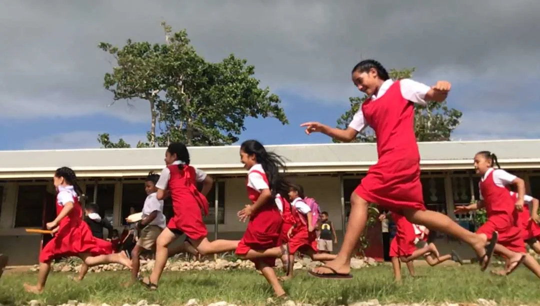 A streak of red rushes past the camera from the school uniforms of Tongan girls on the playground of their primary school in Nuku'alofa. Education in the Kingdom of Tonga has long been a priority, but gaps in the quality of education will require a …