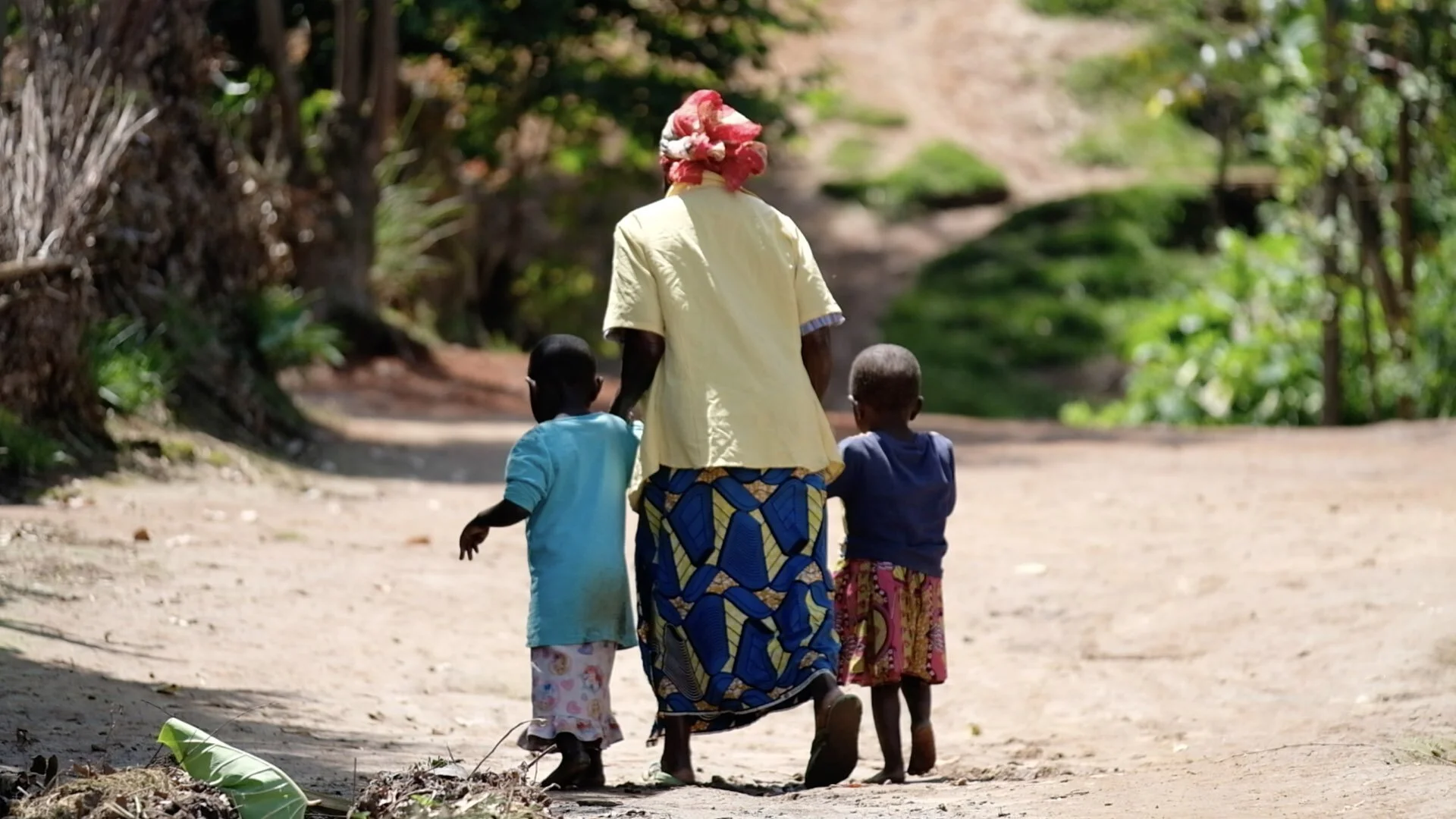 Veronique walks across the road with her two grandchildren. She says it’s not easy to feed two children at her age without land to grow food. UNICEF supports her with food and medicine to ensure the children stay healthy. A case worker checks in on …