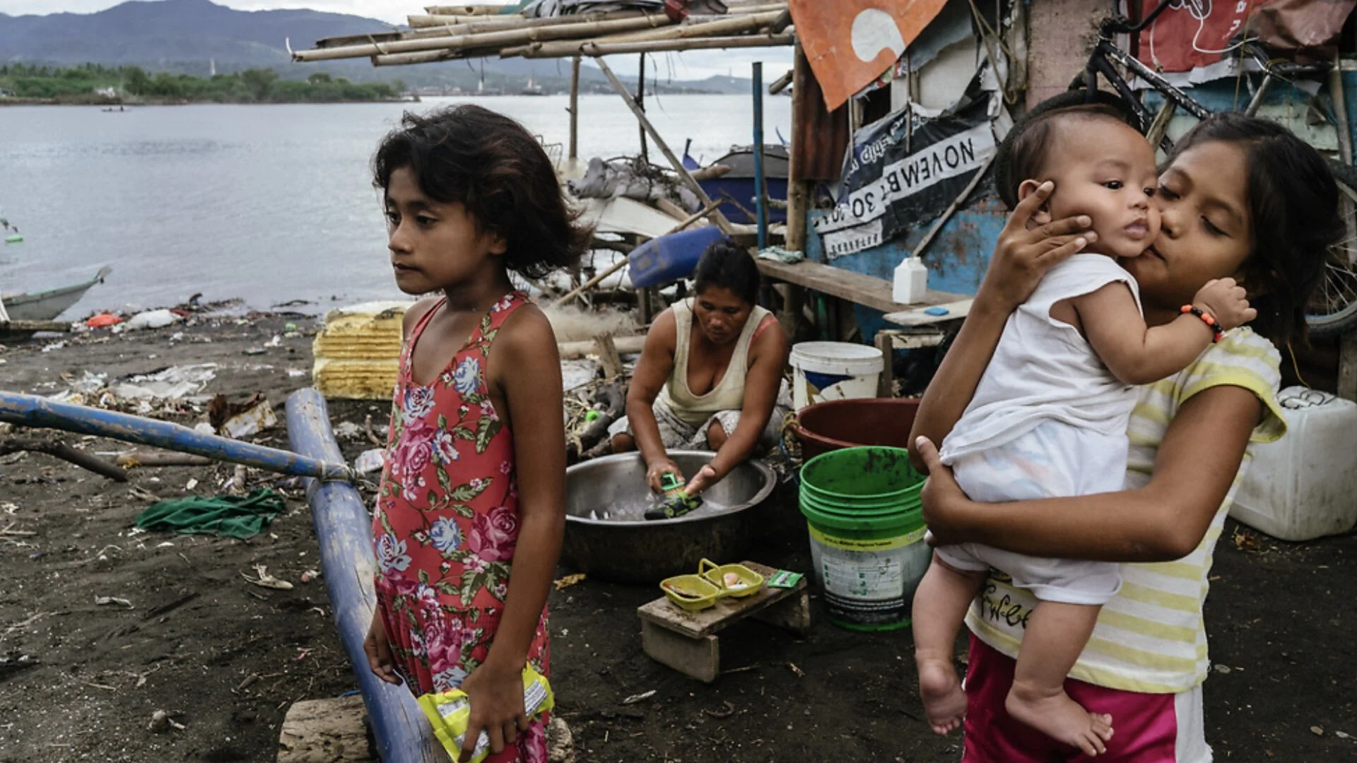 Phillipines: Badjao sisters stand in front of their makeshift home as their mother washes clothes in Wawa, Batangas. Disparagingly labelled as "sea gypsies," Badjao follow the movements of the sea rather than the borders of the land, never quite bel…