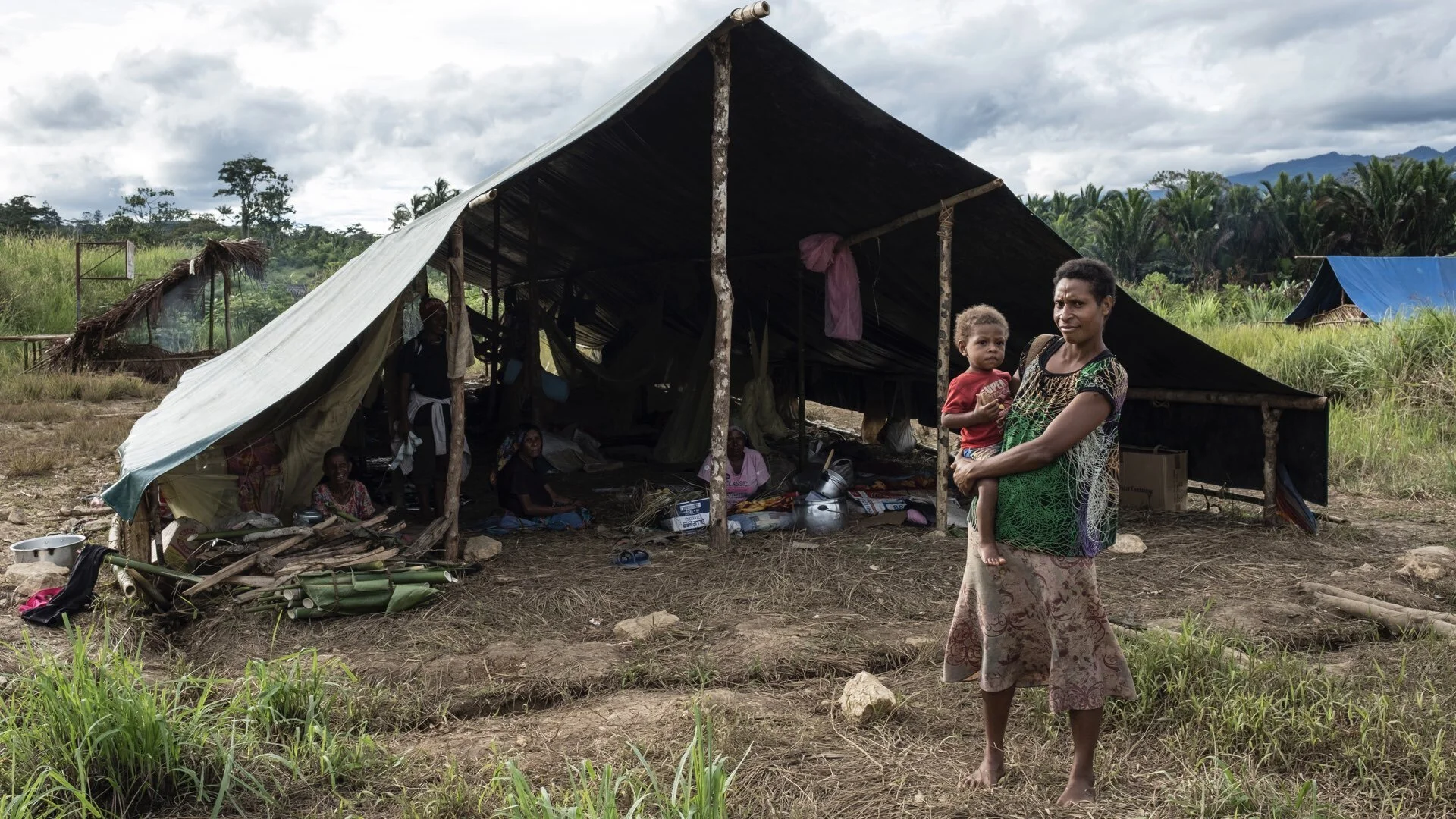 Papua New Guinea: Fiona, 28, stands with Silver Star, her one-year-old son, outside makeshift tent where they have been living since a 7.5 magnitude earthquake on 26 February 2018 destroyed their home in nearby Daga village, in Pimaga, Papua New Gui…