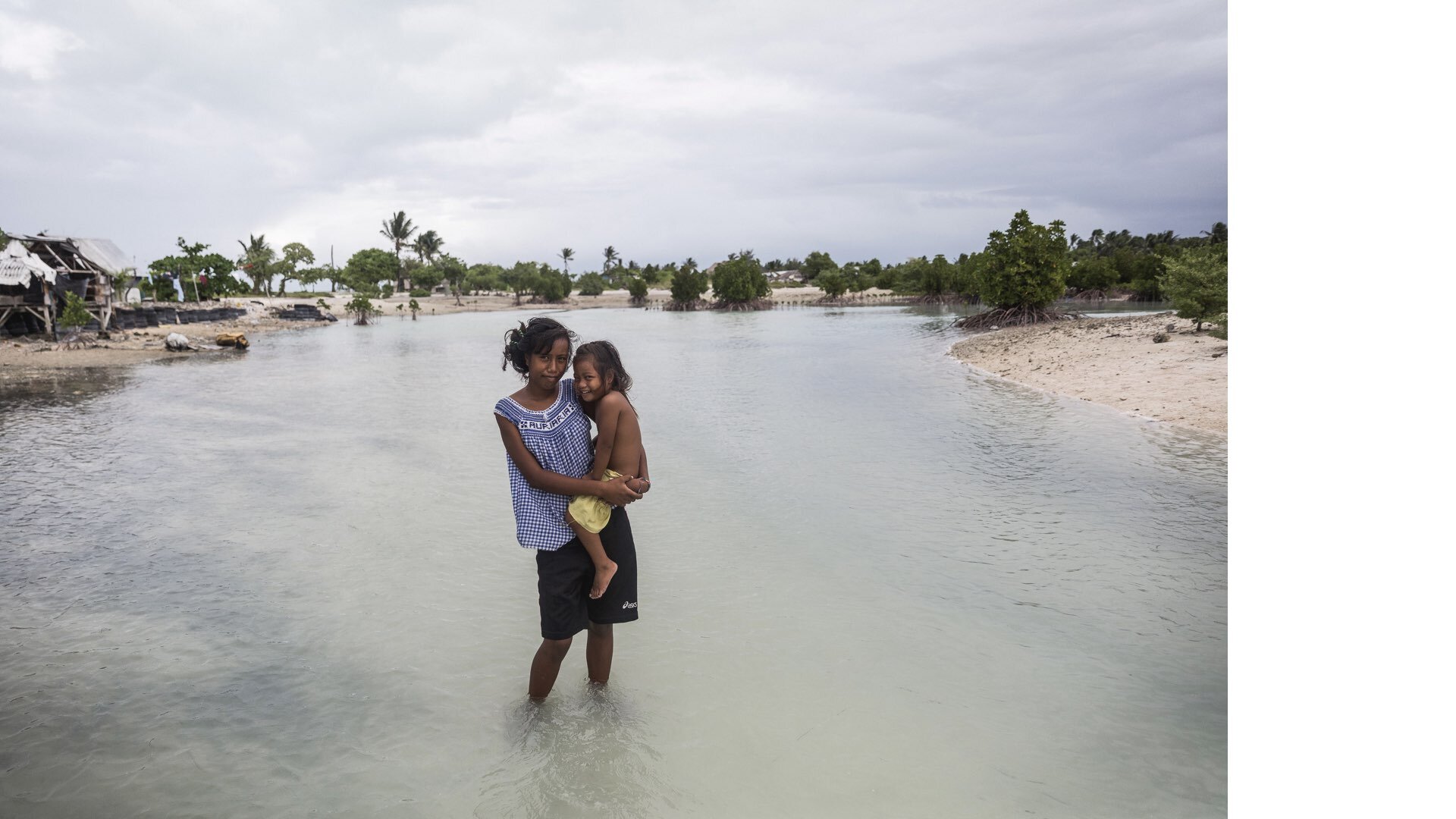 Kiribati: Taronga, 16, holds her two-year-old sister Teaborenga while standing in a flooded area in the village of Eita, South Tarawa, Kiribati, Thursday 28 January 2016. Eita is one of many localities on Tarawa atoll that regularly floods at high t…