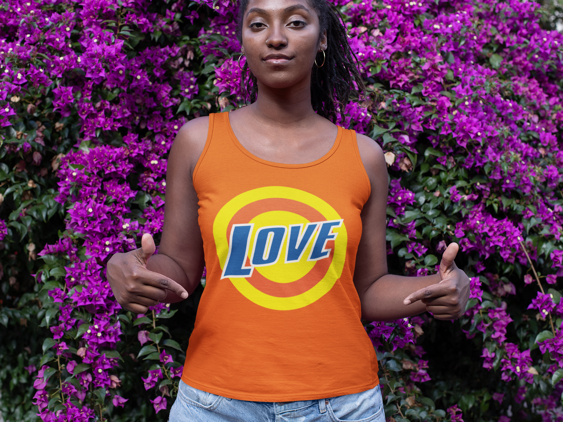 mockup-of-a-woman-showing-her-tank-top-in-front-of-a-wall-of-flowers-32058.png