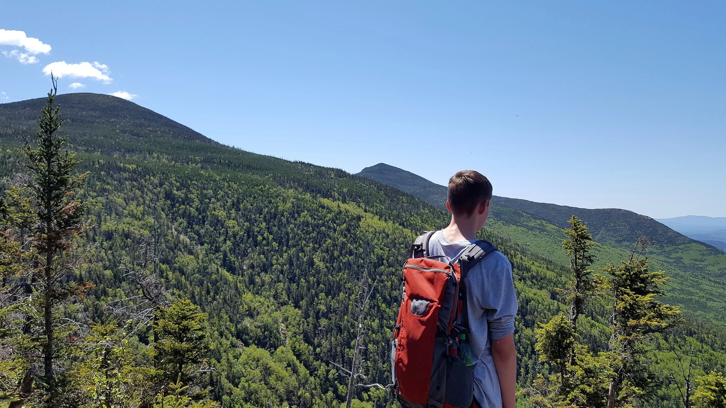 Henry looking down at the pond with South Brother, Mount Coe, and Mount O-J-I