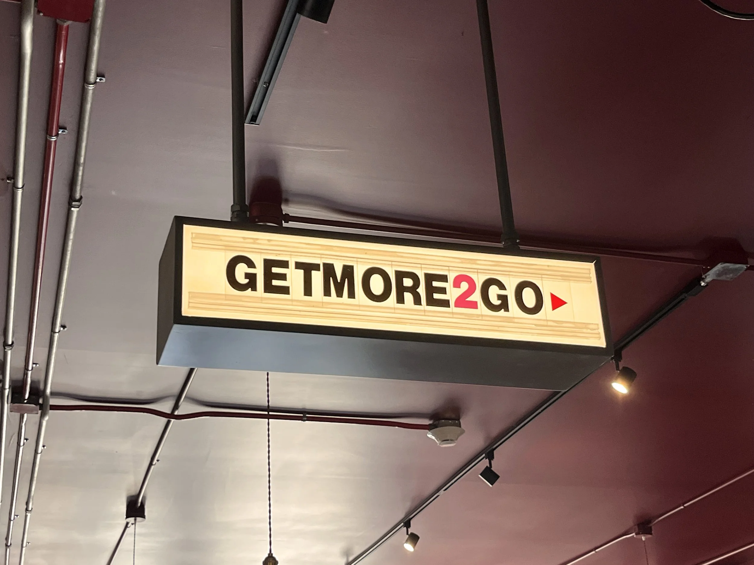  Back Home Barbecue  Little Rock, Arkansas  “GET MORE TO GO” &amp; “RESTROOMS” hanging interior sign with back-lighted changeable lettering  Sign development and unit design © Chuck Mitchell  Branding and signage package design creative developed by 