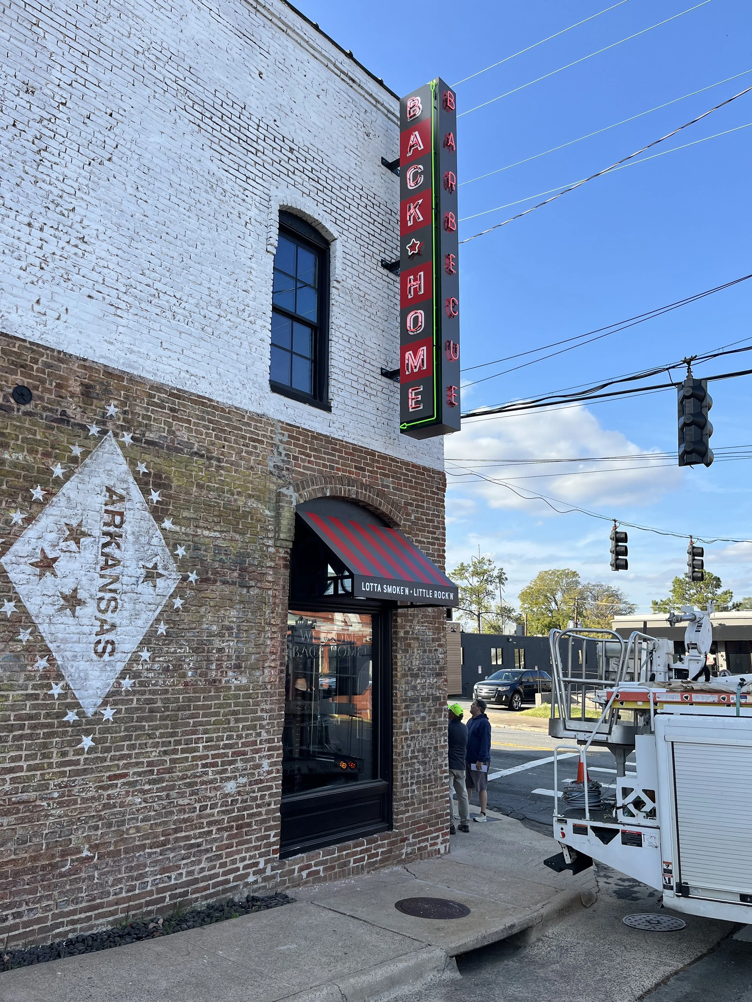  Back Home Barbecue  Little Rock, Arkansas  East face exterior neon blade sign, window neon, and awning with tag line “LOTTA SMOKE’N - LITTLE ROCK’N” written by Chuck Mitchell  Branding and signage package design creative developed by Chuck Mitchell 