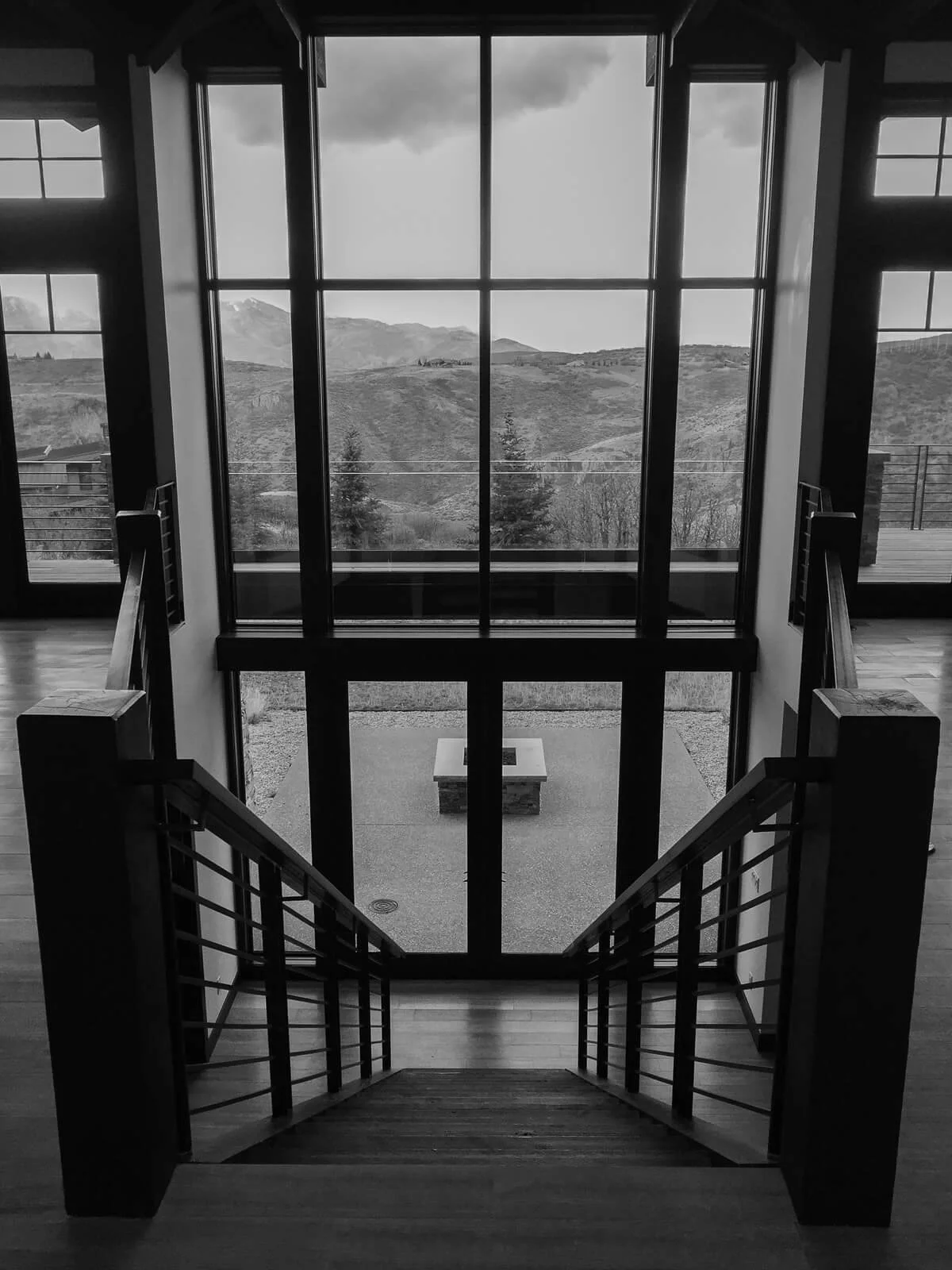 Interior staircase leading to a patio, framed by tall windows with a mountain view beyond.
