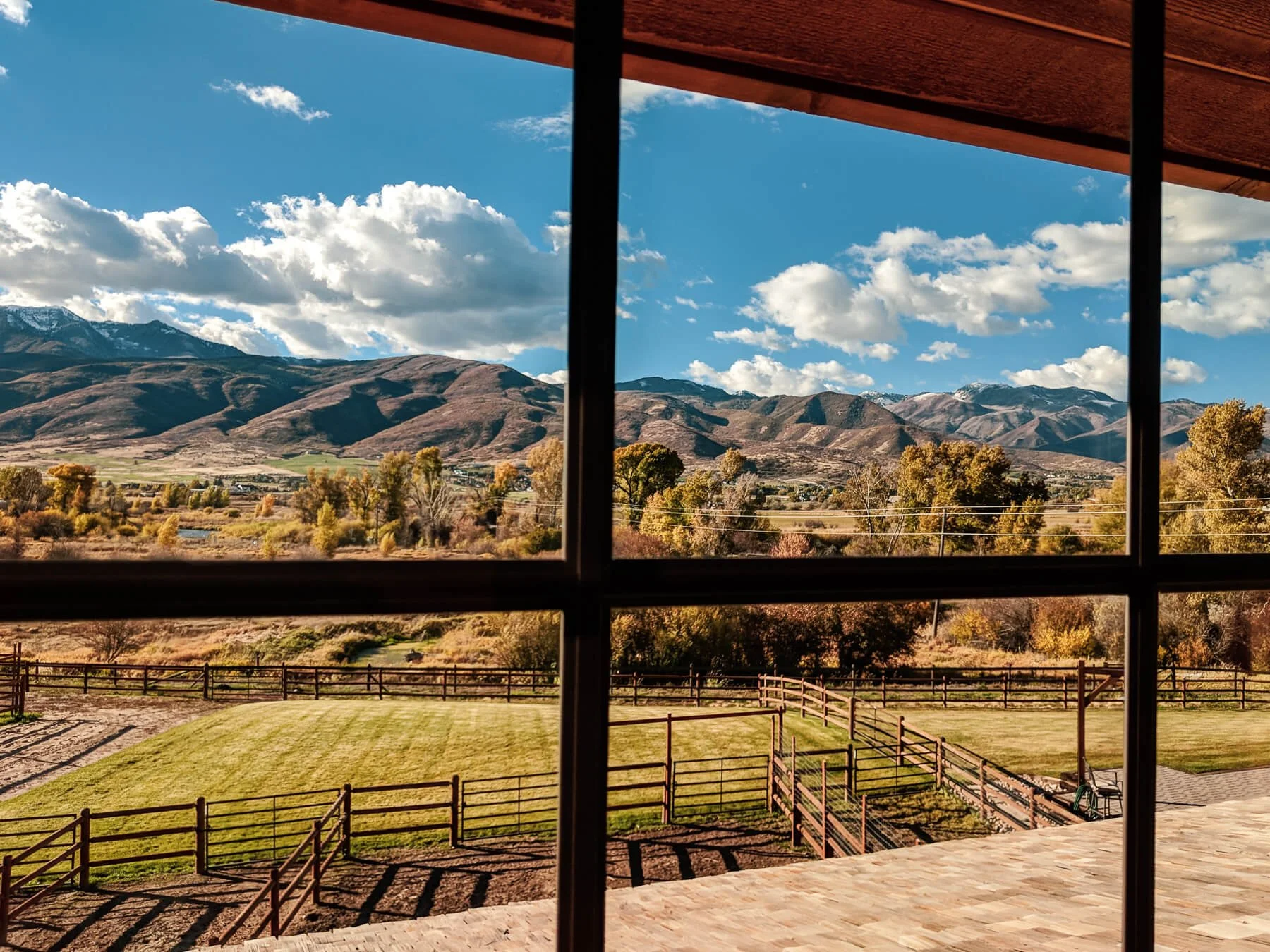 Mountain landscape framed by black metal windows, with partly cloudy skies in the distance.